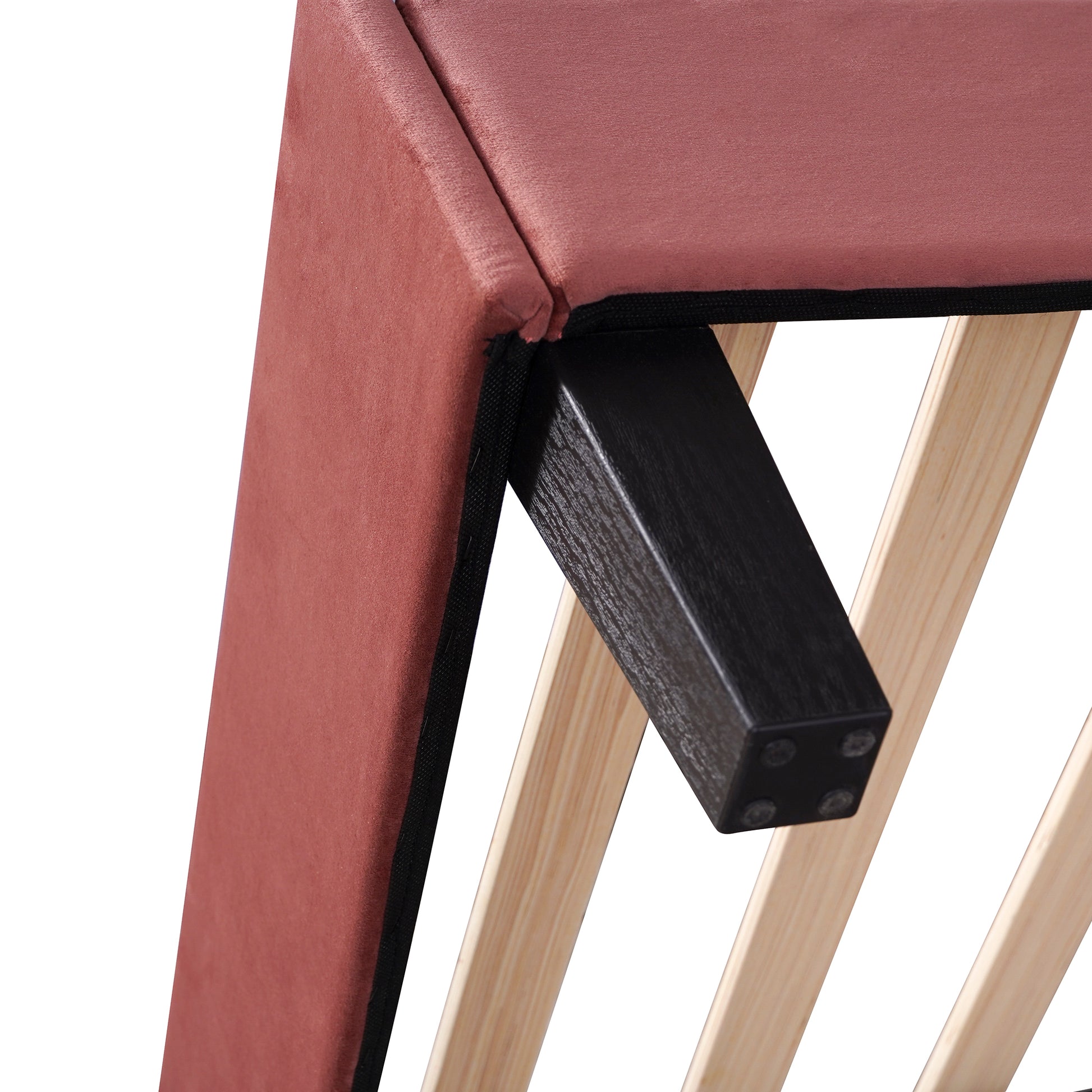 Dusty rose velvet upholstered bed frame detail with black wooden leg