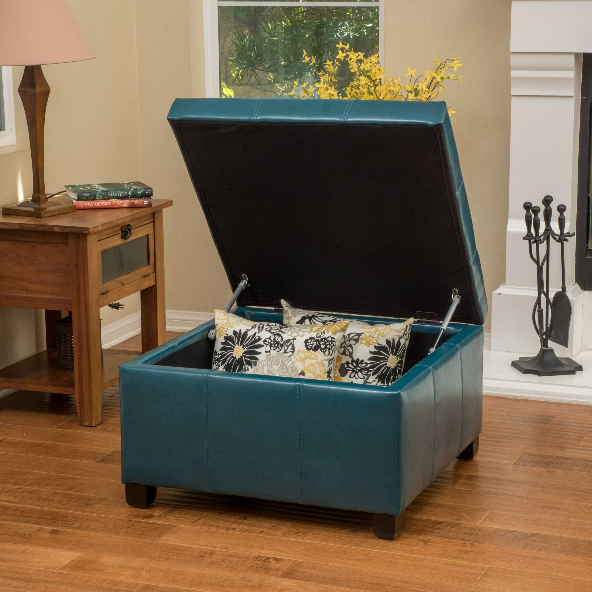 Teal faux leather storage ottoman with lid open revealing pillows