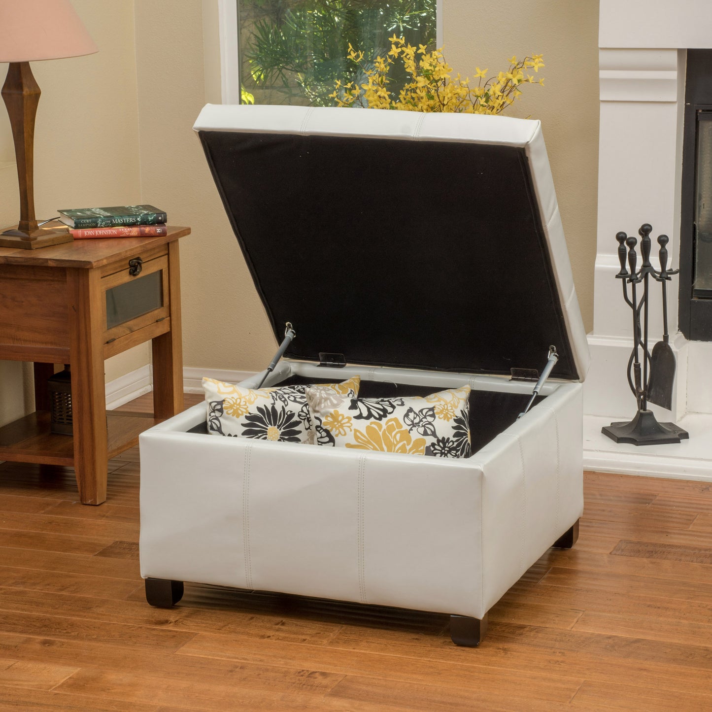 White faux leather storage ottoman with decorative pillows
