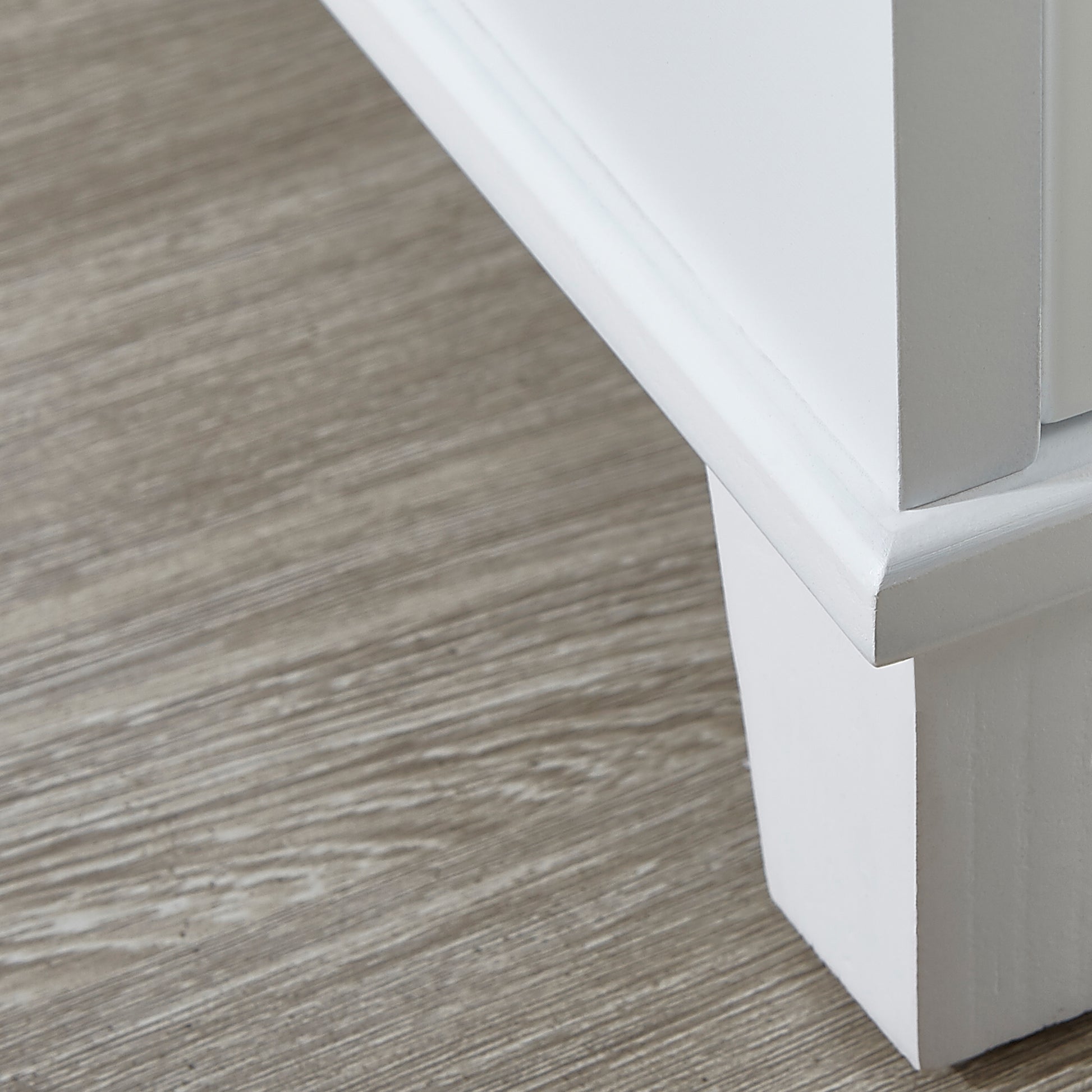 White painted wood cabinet corner on a gray woodgrain floor