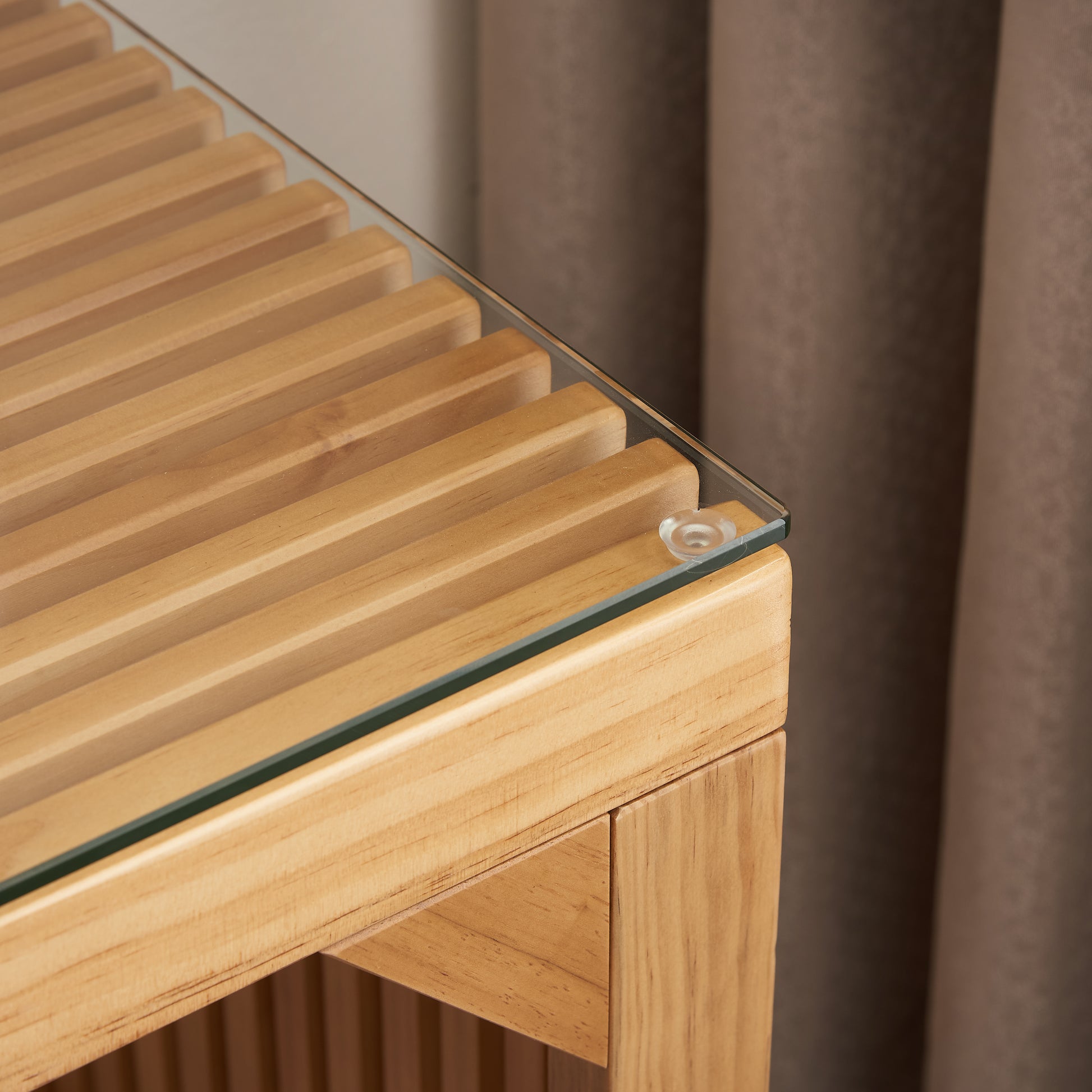 Closeup of a light wood slatted bench with a clear glass top