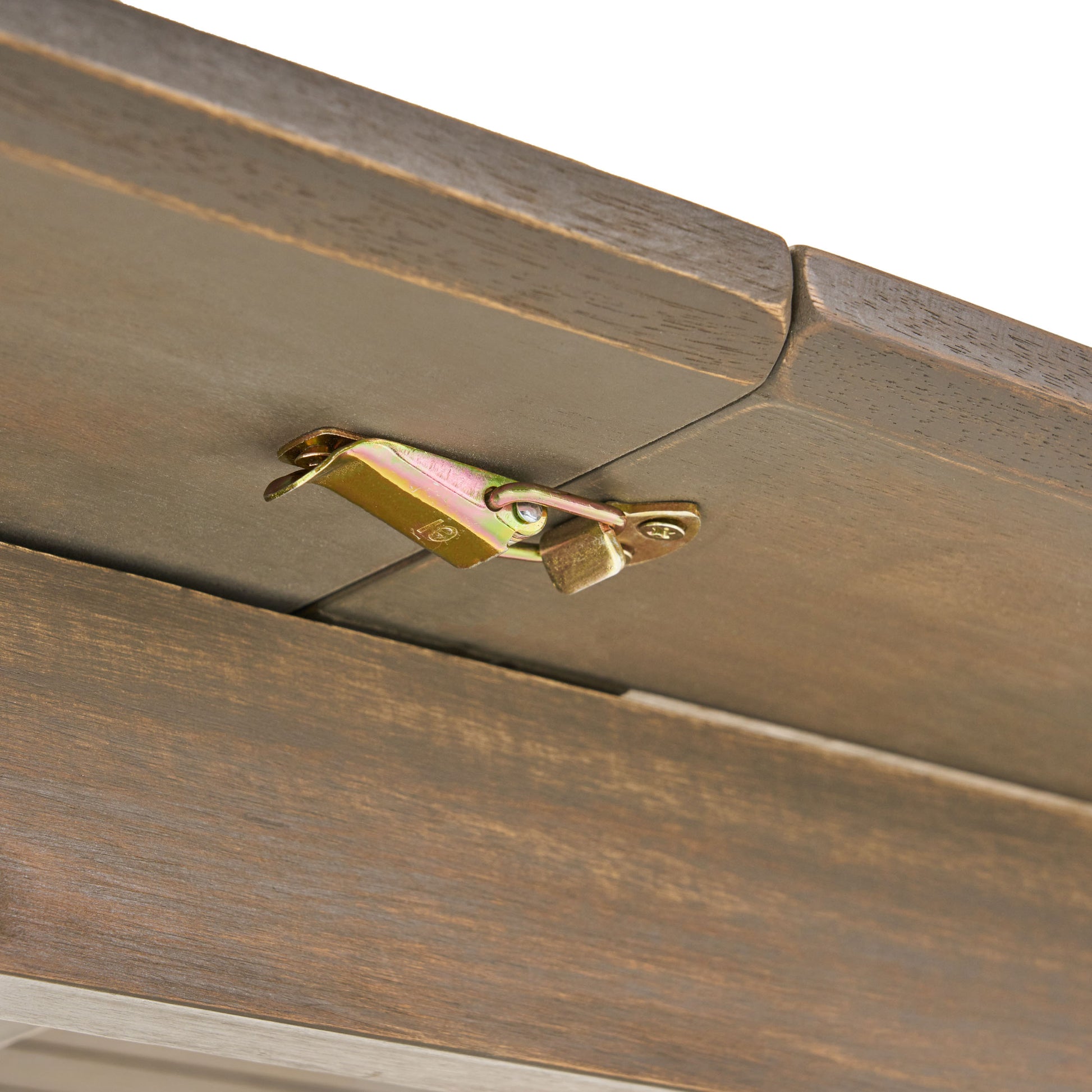 Closeup of a brass latch mechanism on a dark wood grain tabletop