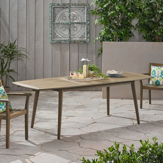 Extendable teak patio dining table with angled legs and decorative centerpiece