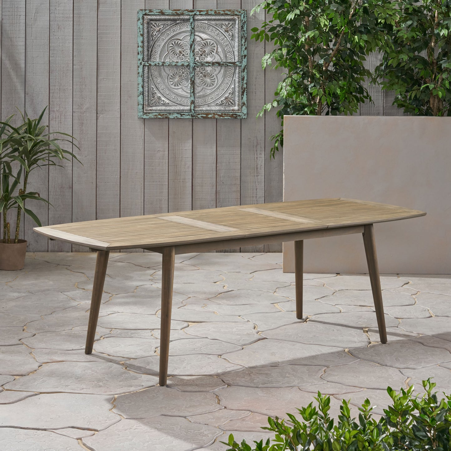 Light brown slatted wooden outdoor dining table with tapered legs