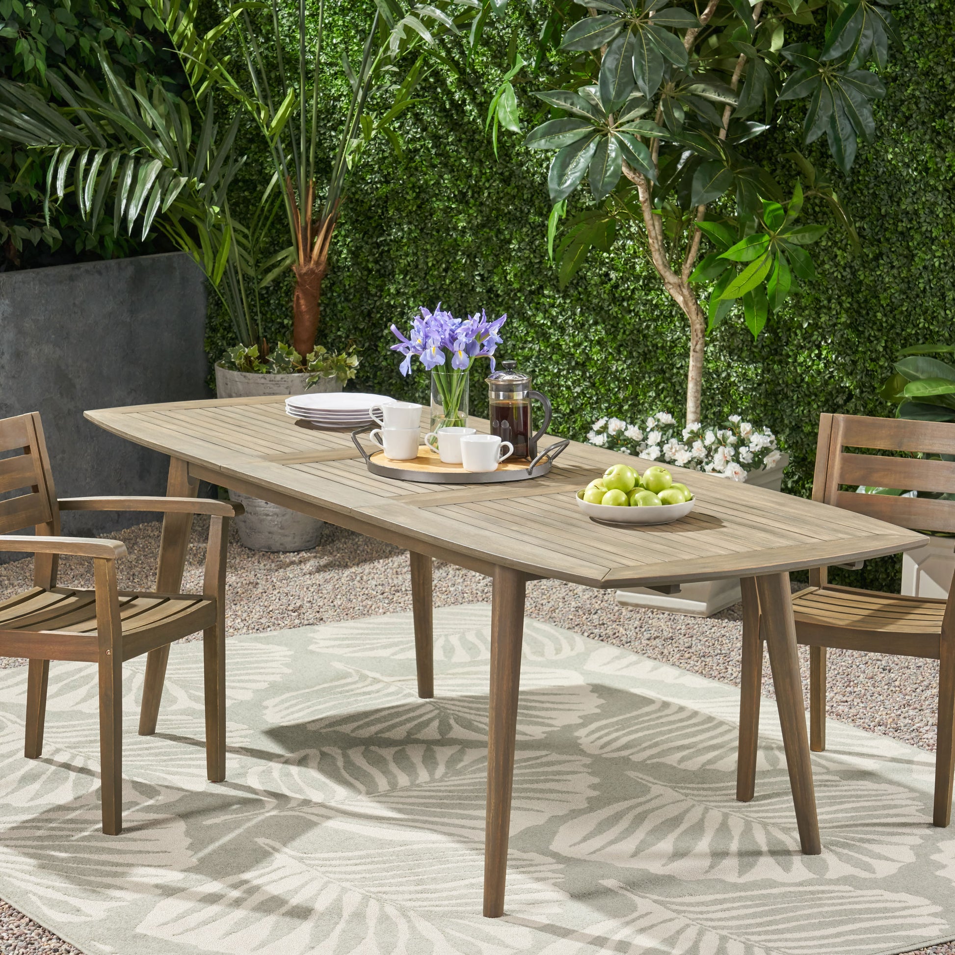 Wooden outdoor dining table and chairs with a tray of coffee cups and fruit
