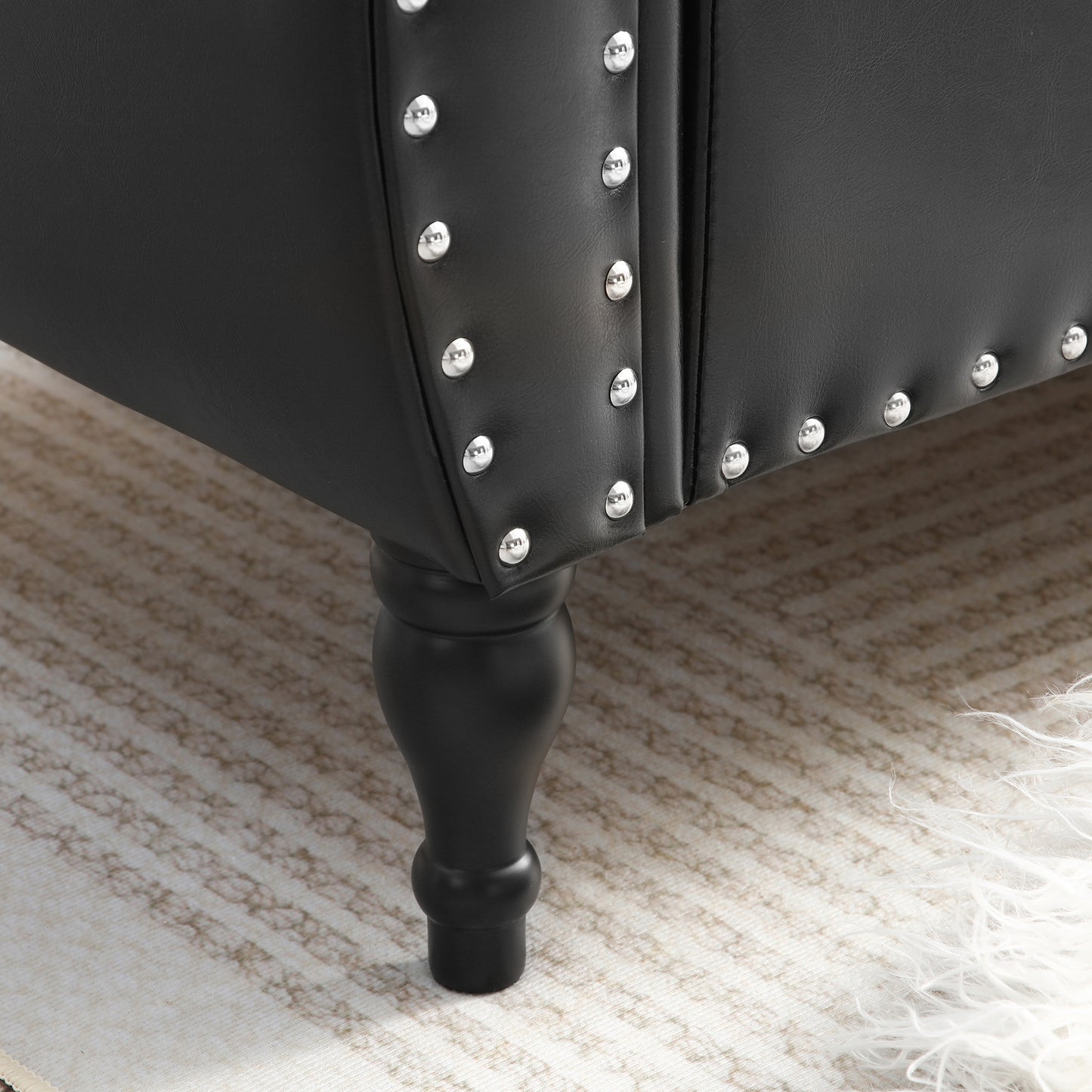 Black faux leather armchair with silver stud detailing and turned wooden leg
