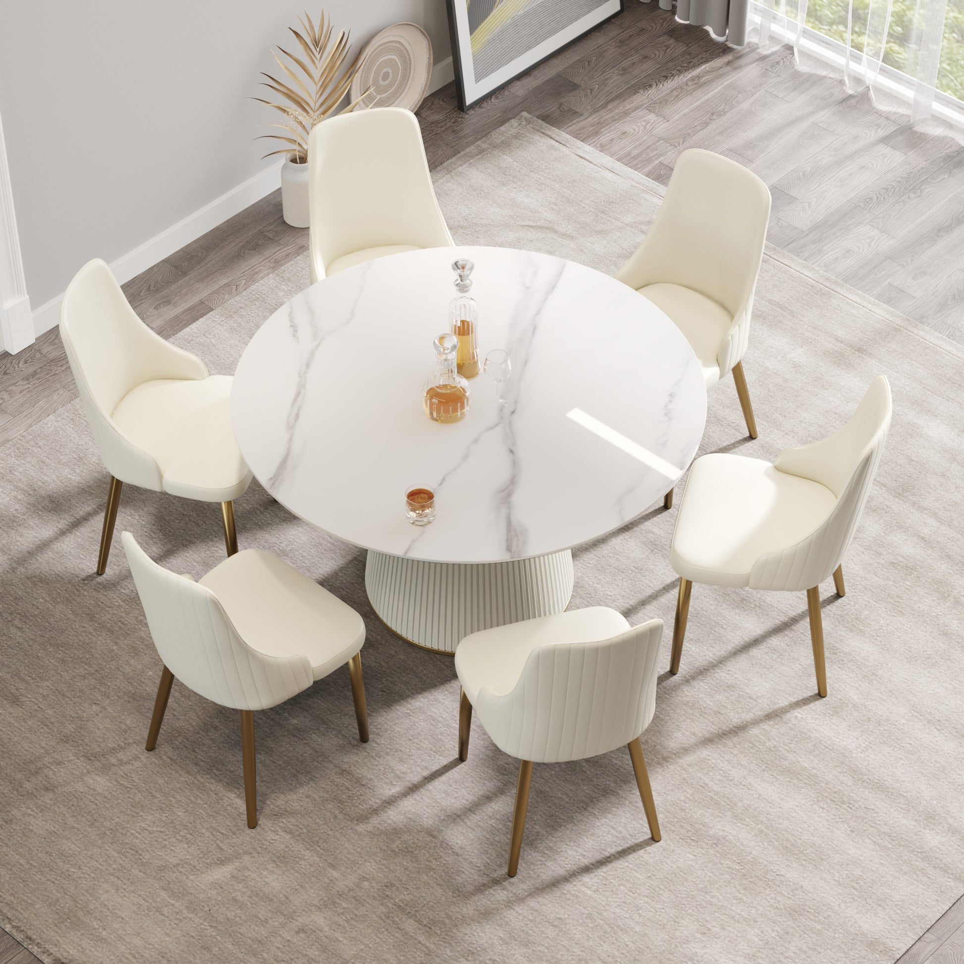 Cream upholstered dining chairs with gold legs surrounding a round white marblelook table