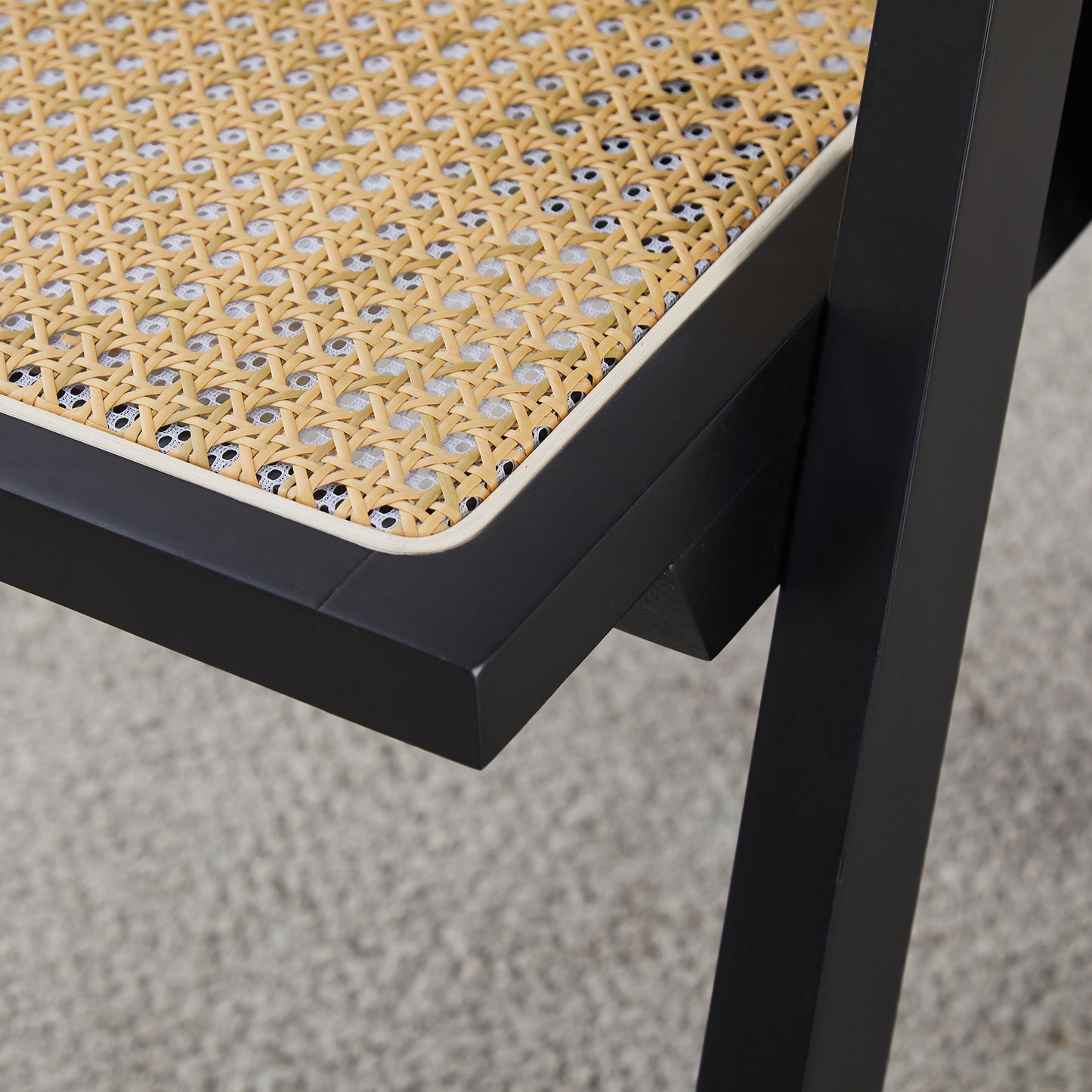 Black metal chair frame detail with woven cane seat