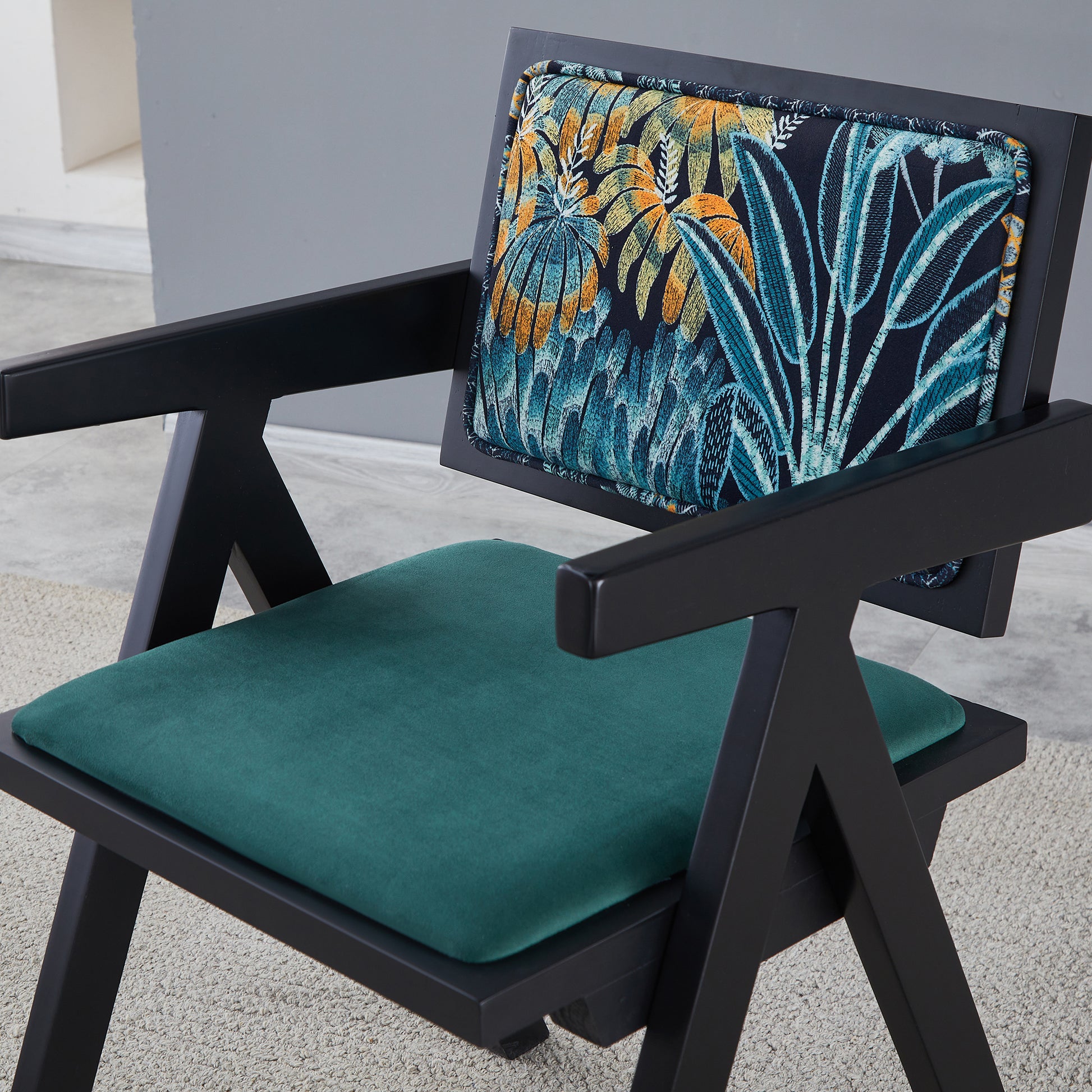 Black armchair with forestgreen velvet seat and tropical print backrest