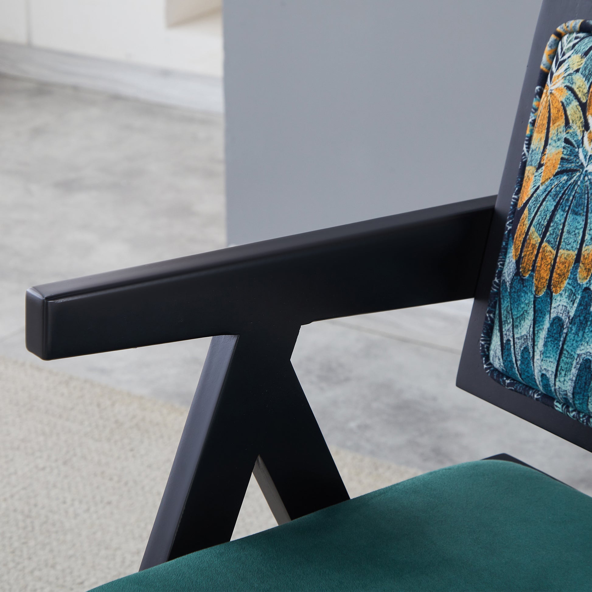 Black armrest chair with a plush emerald green velvet seat cushion
