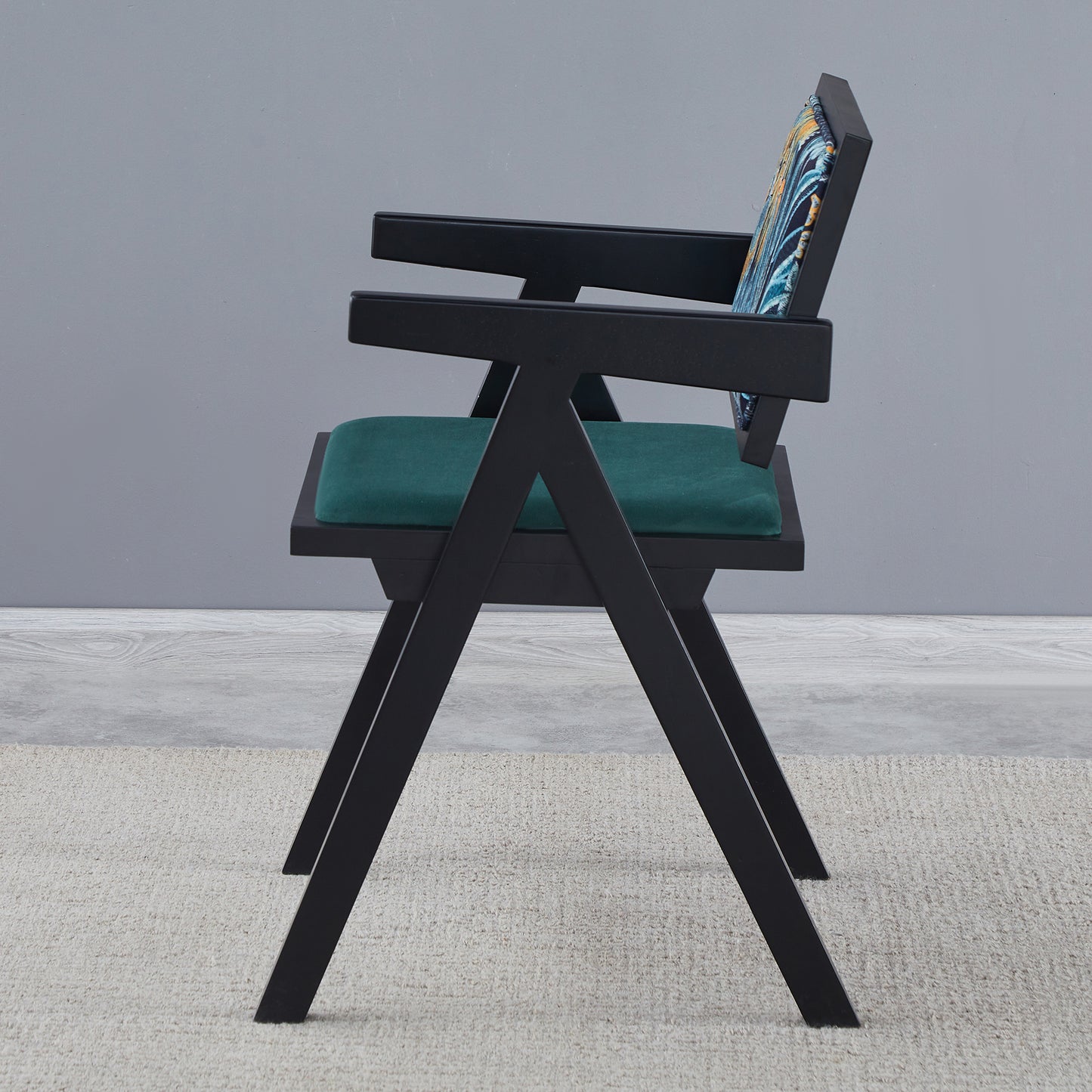 Modern black armchair with teal velvet seat and abstract patterned backrest