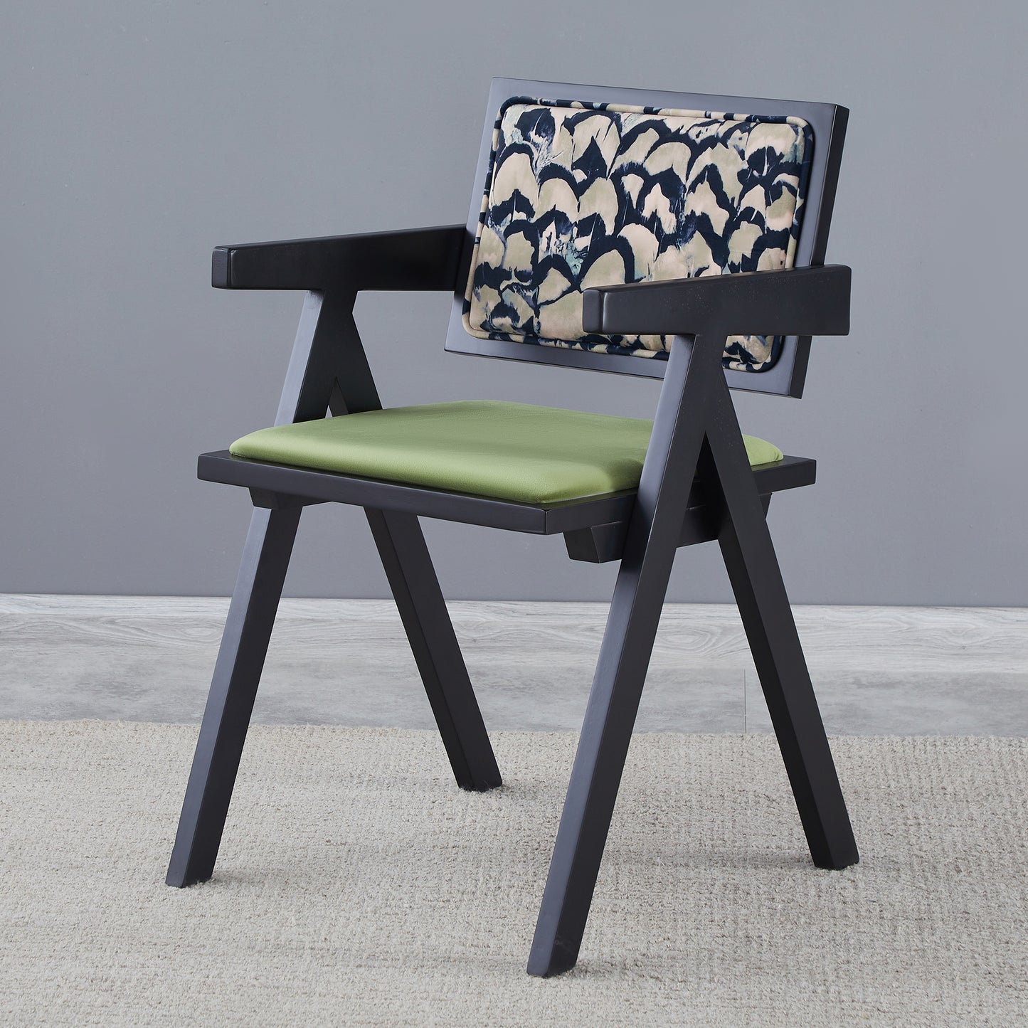 Black armchair with green seat cushion and abstract patterned backrest