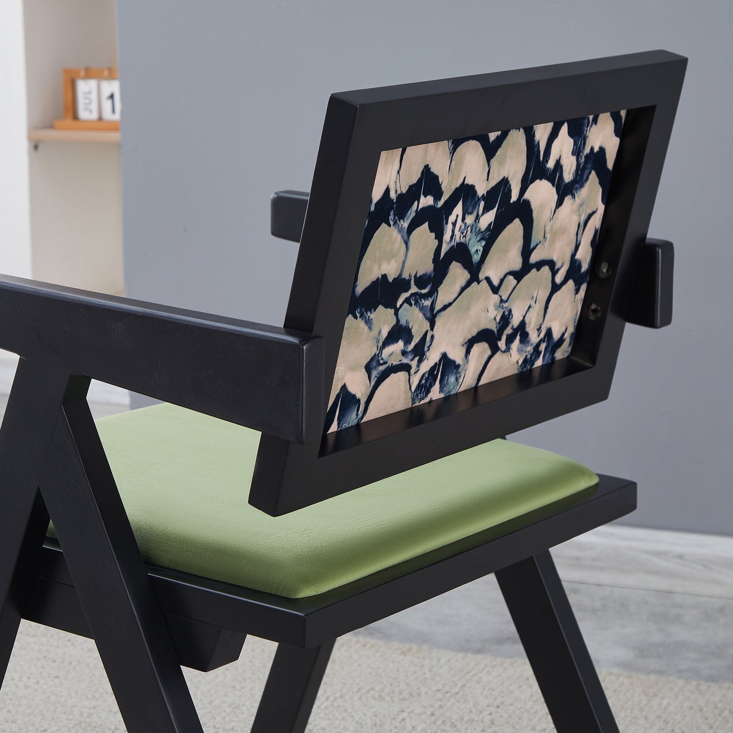 Black wooden chair with abstract patterned back and green seat