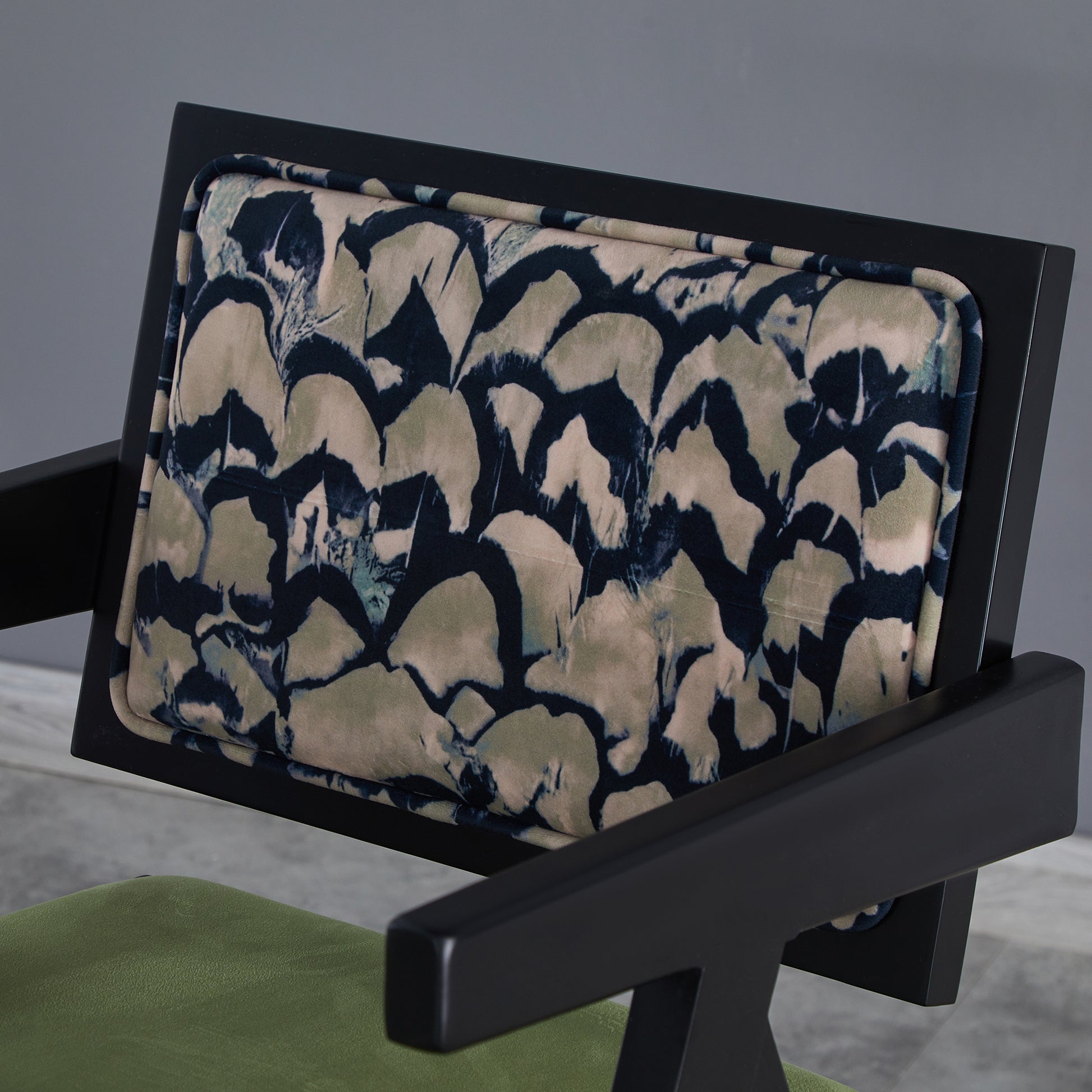 Black armchair with abstract print cushion and green seat