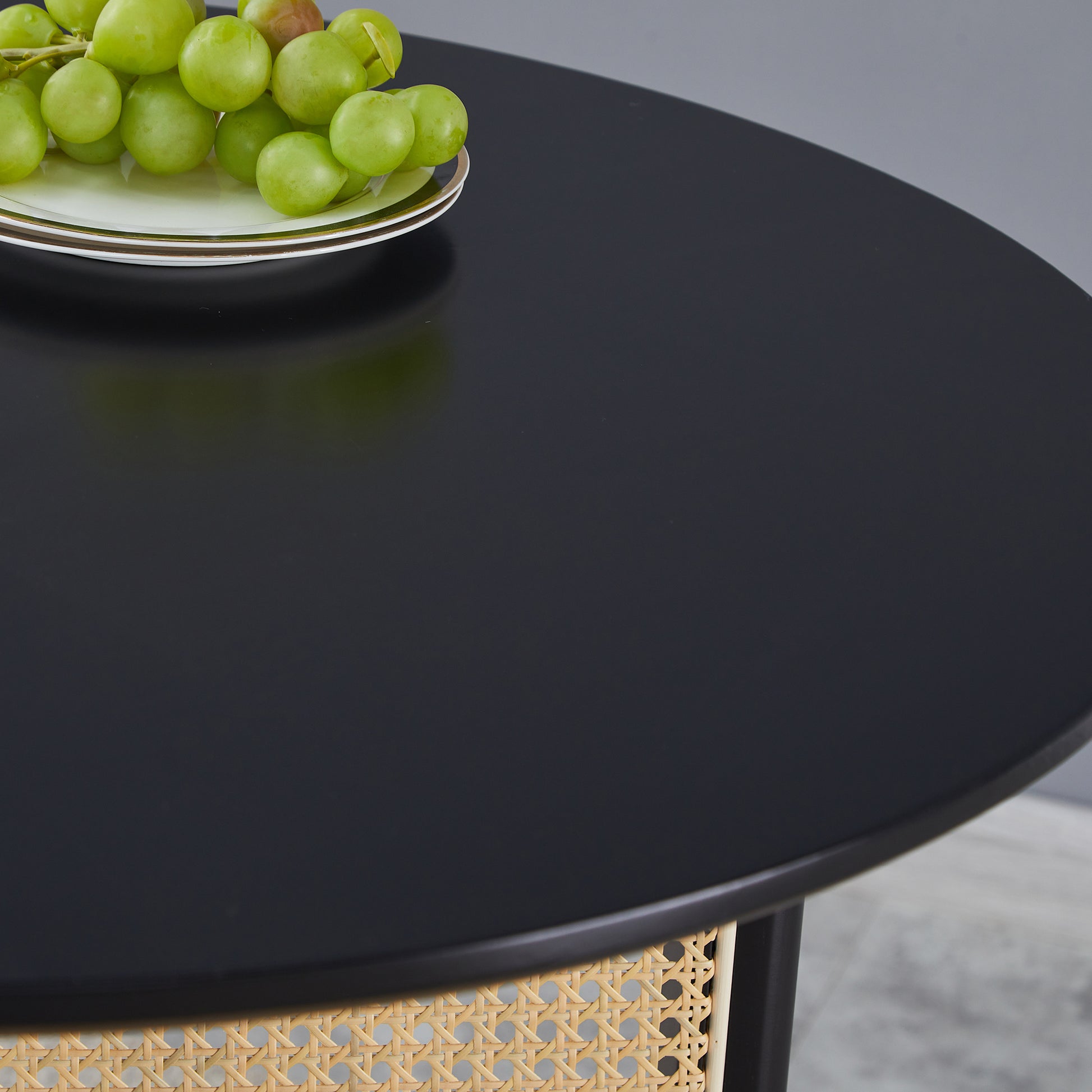 Black round dining table with woven rattan base
