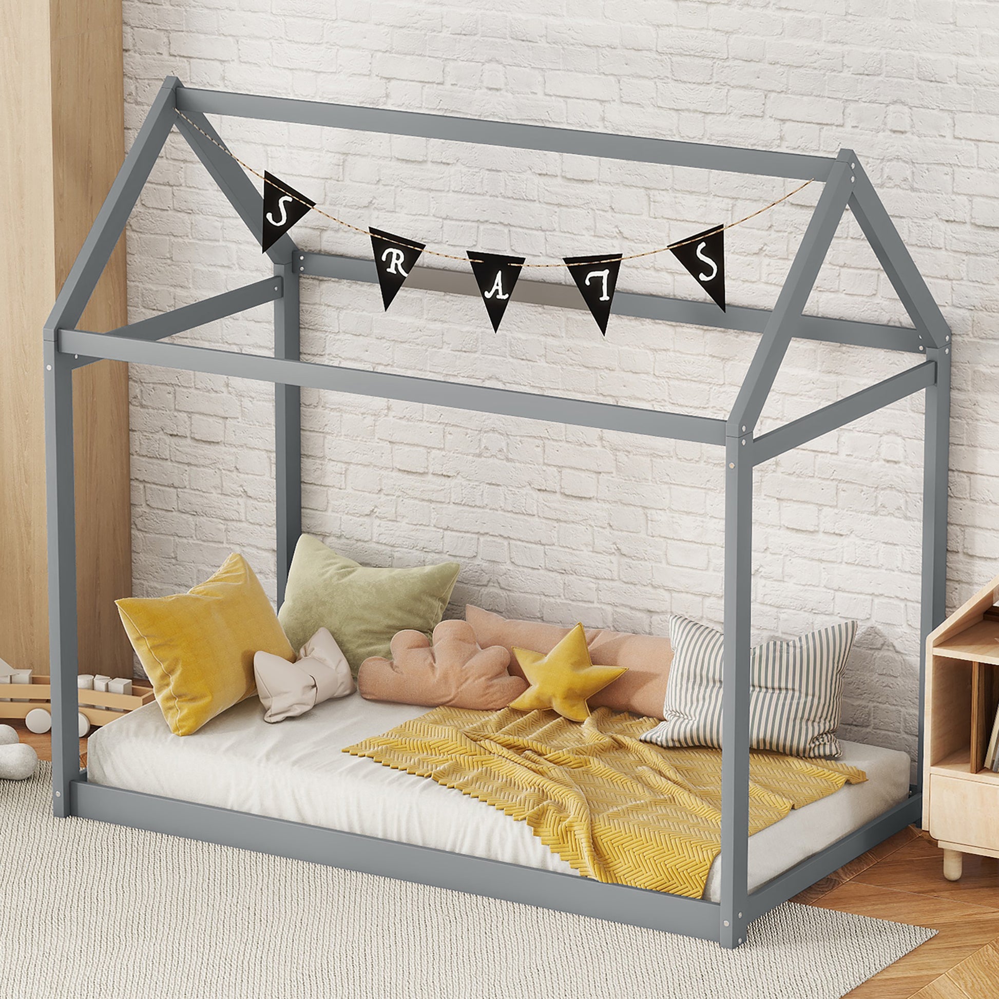 Gray wood toddler bed frame with playful pillows and yellow blanket