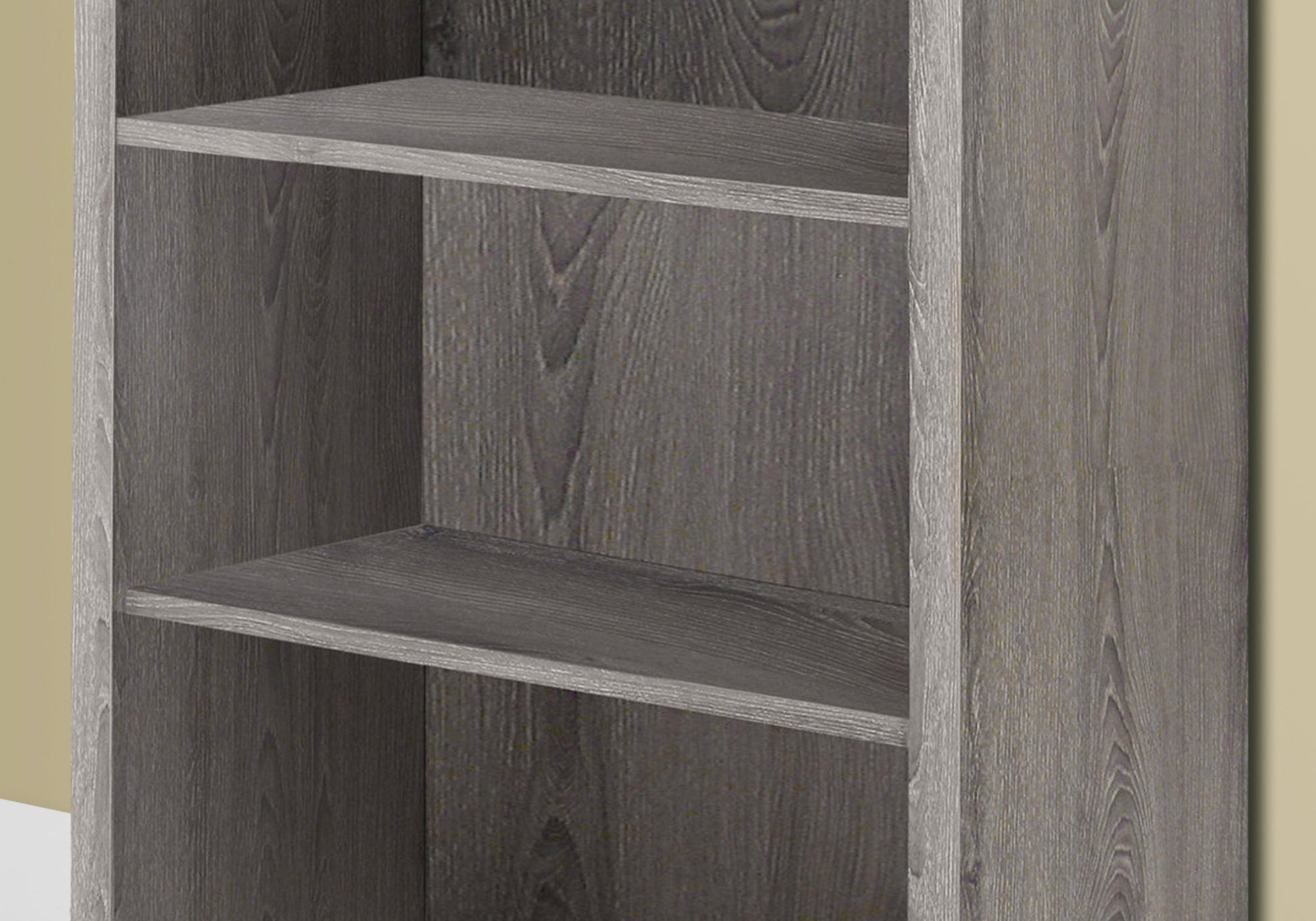 Closeup of a grey wood grain bookshelf with three shelves