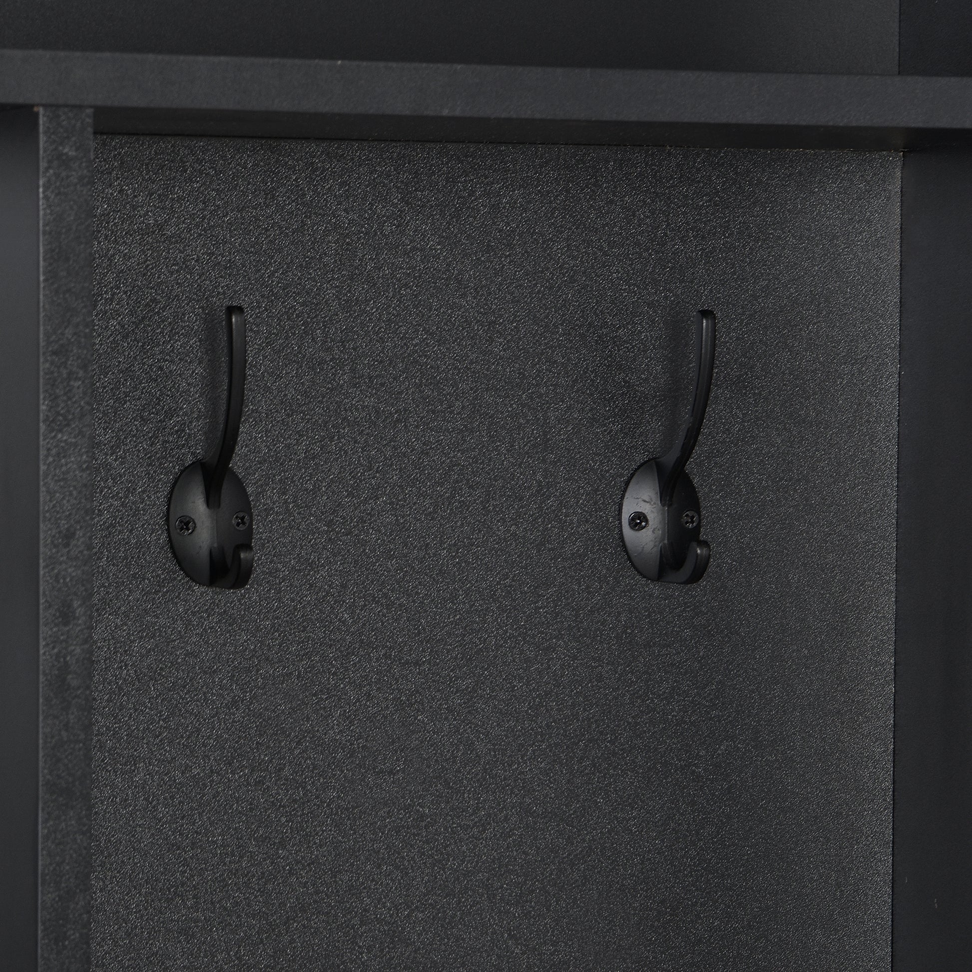Two black metal coat hooks mounted on a textured black panel