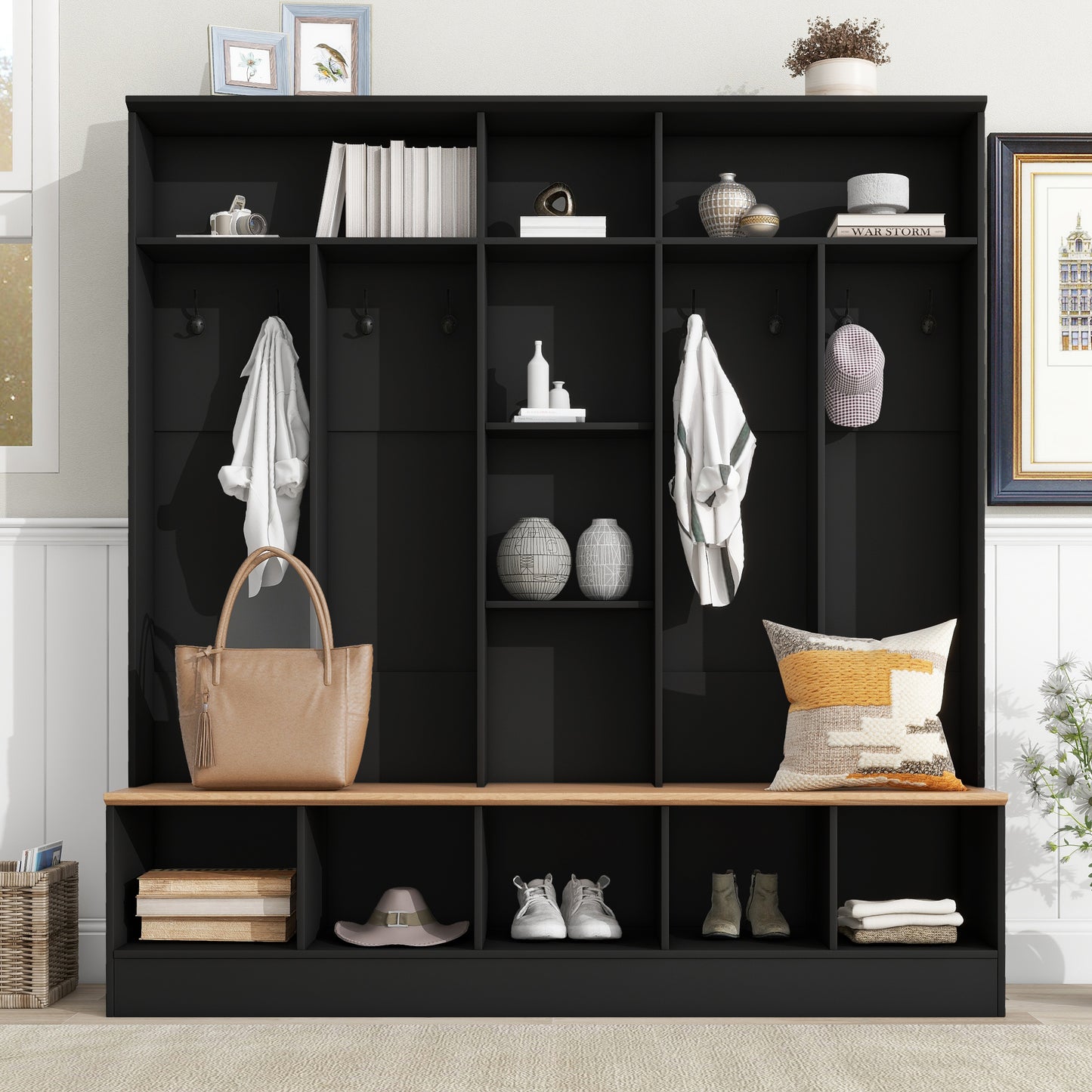 Black entryway bench with hooks and storage compartments holding hats shoes and bags