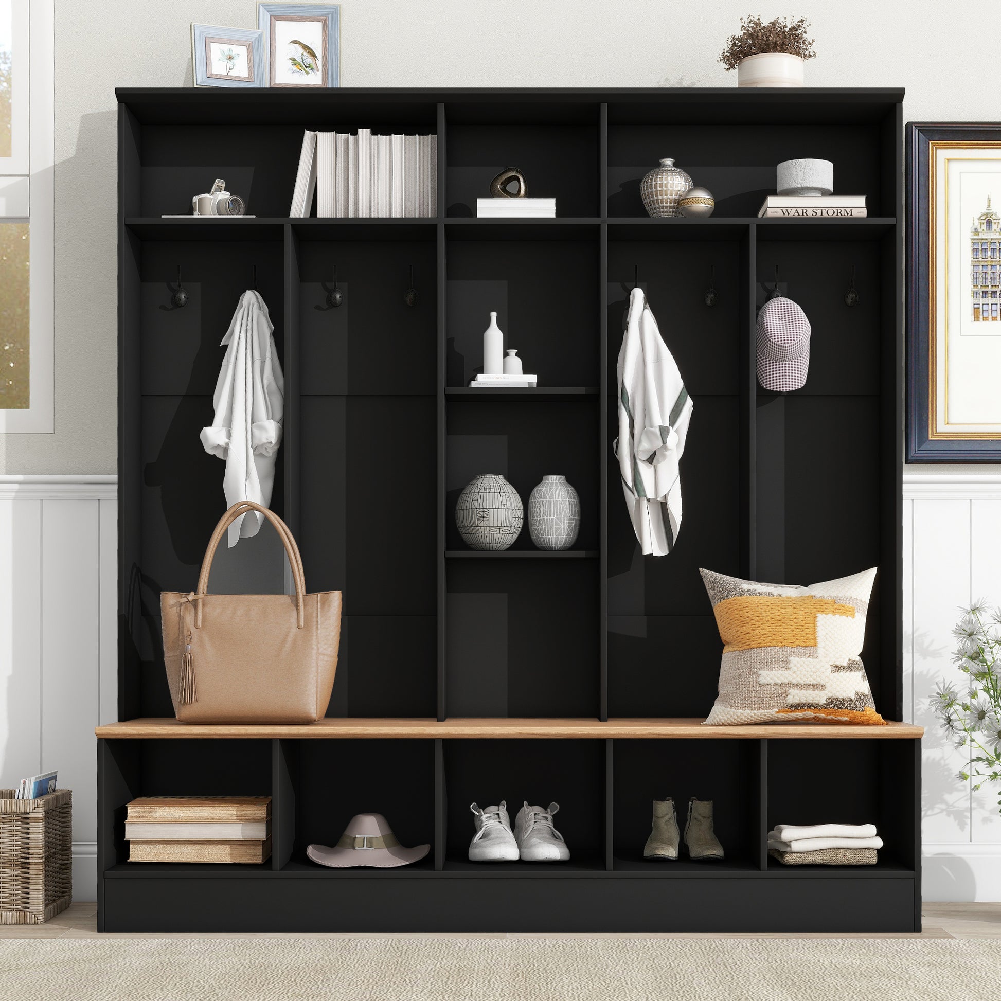Black entryway bench with hooks and storage compartments holding hats shoes and bags
