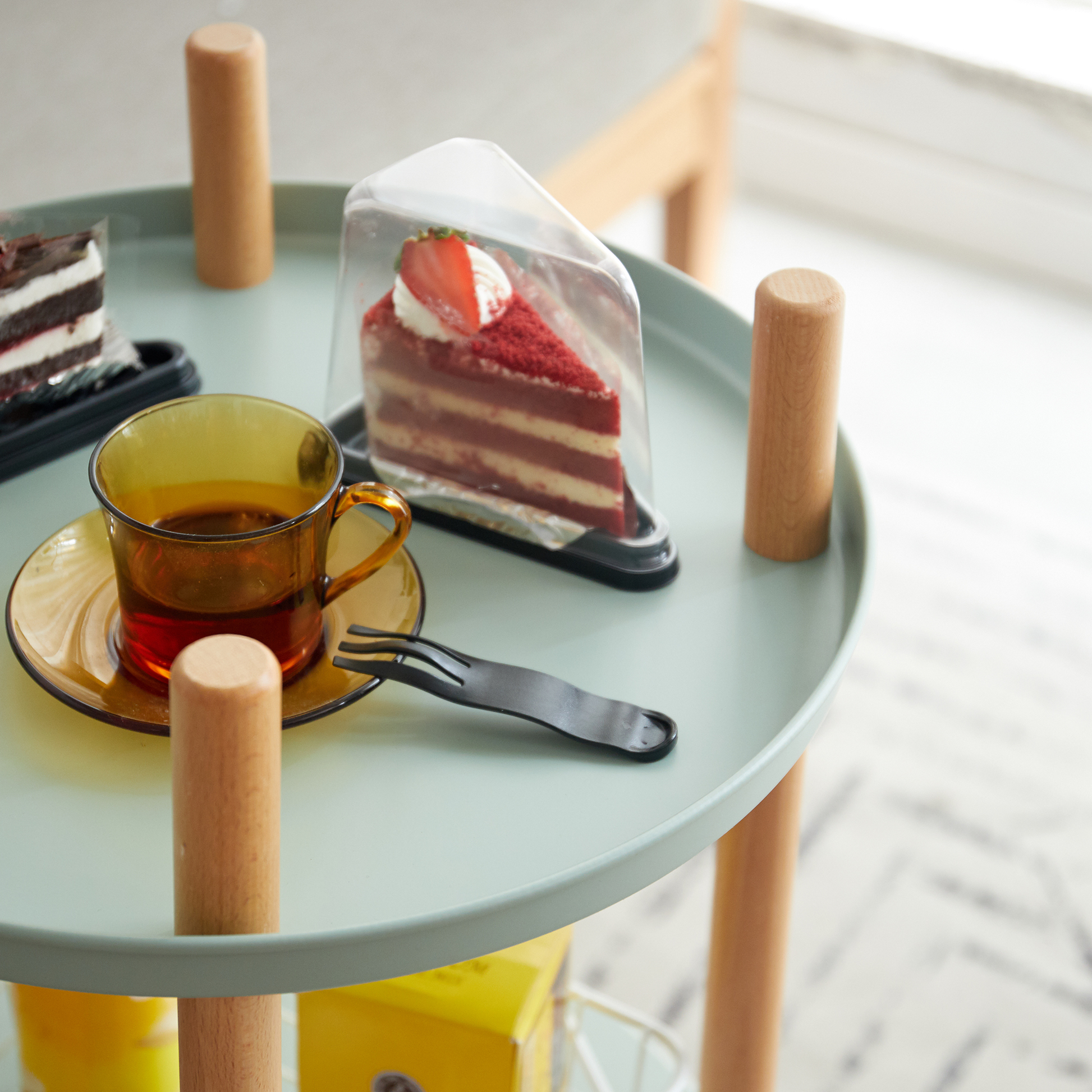 Slice of red velvet cake with strawberry topping on black tray