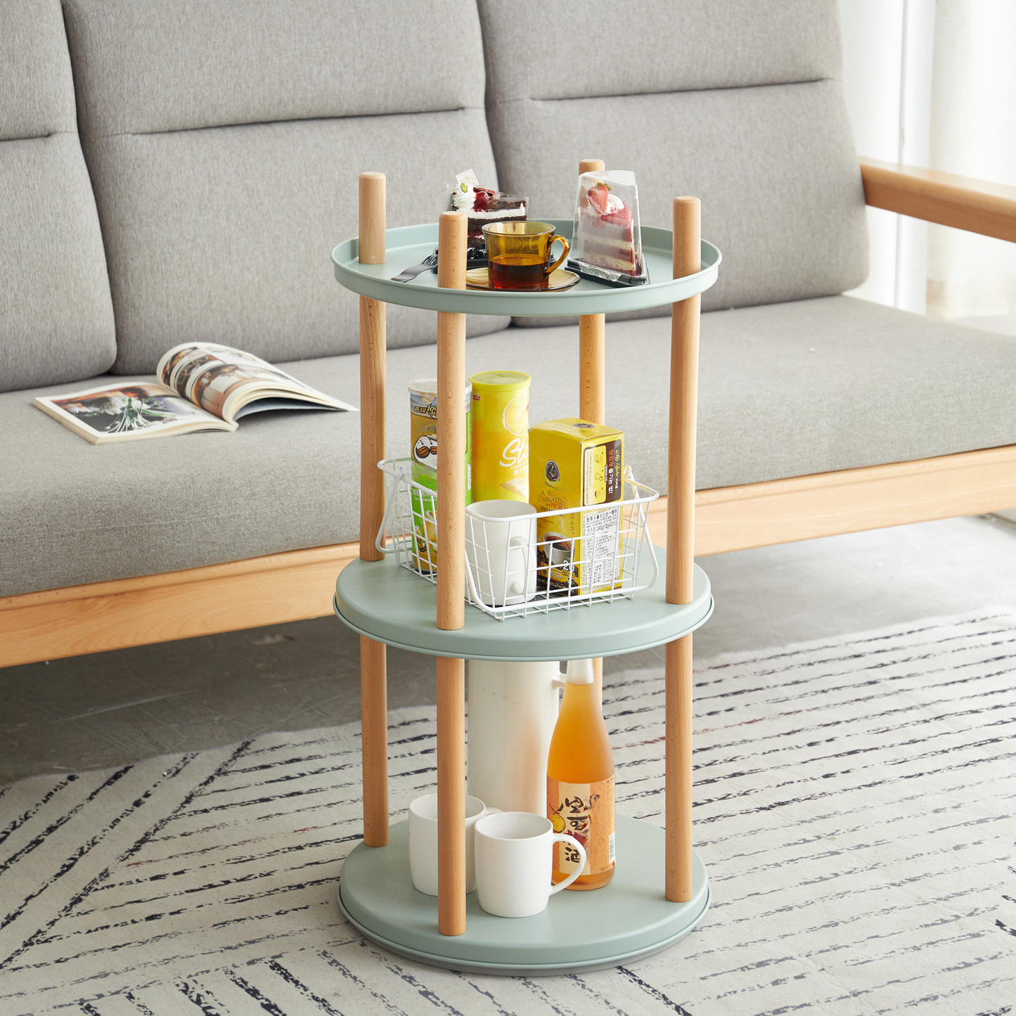 Sage green threetier side table with wood legs holding snacks and drinks