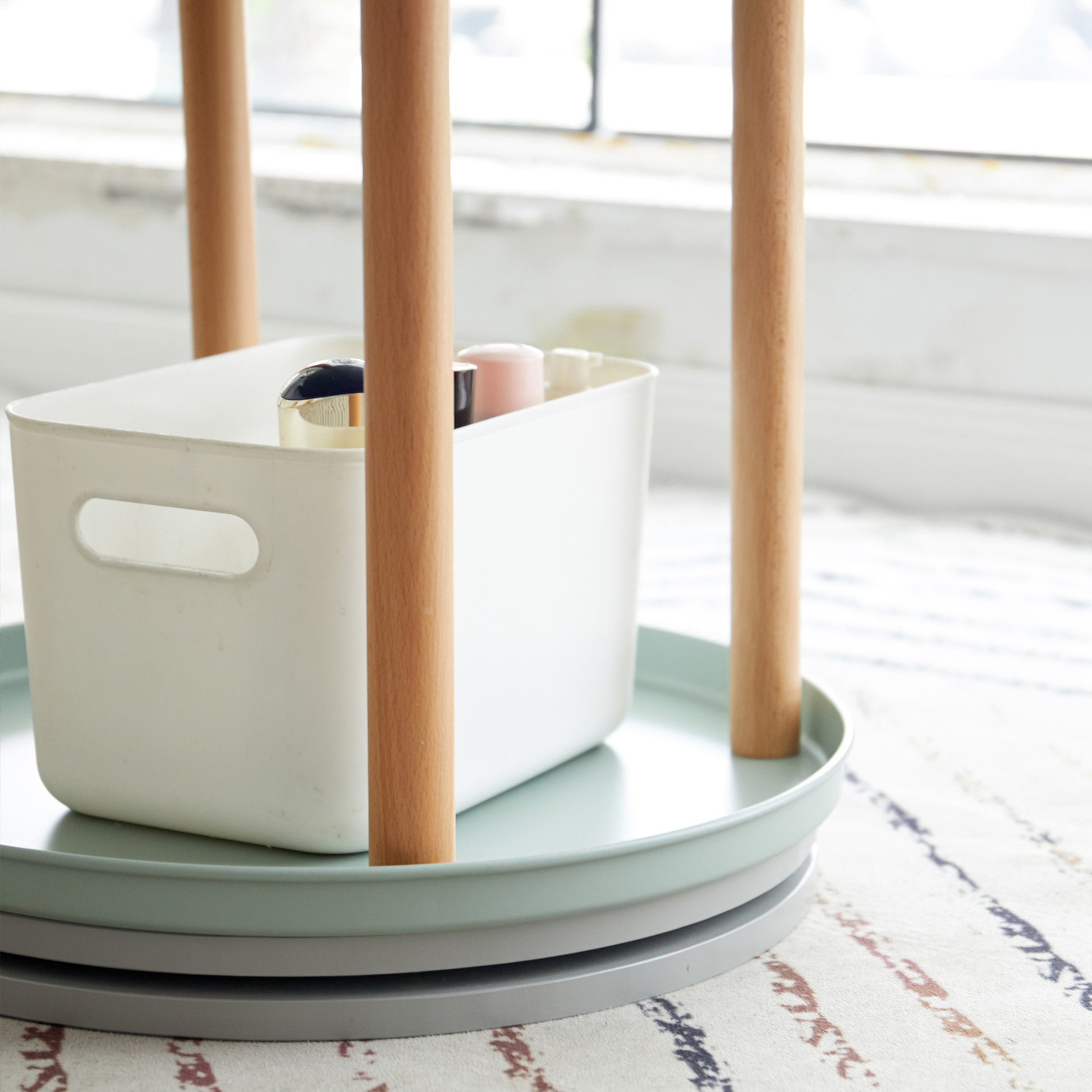 White plastic storage bin with wood accents and cosmetics inside