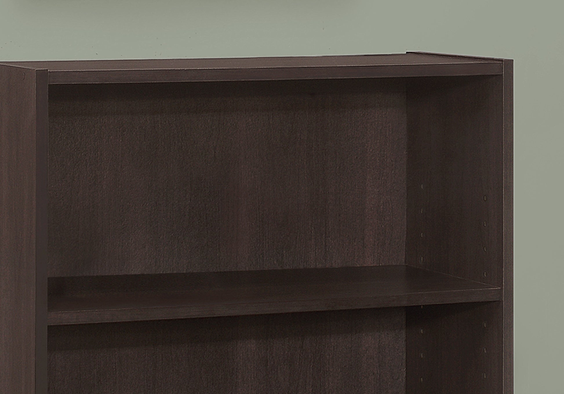 Dark brown particleboard bookshelf with two visible shelves