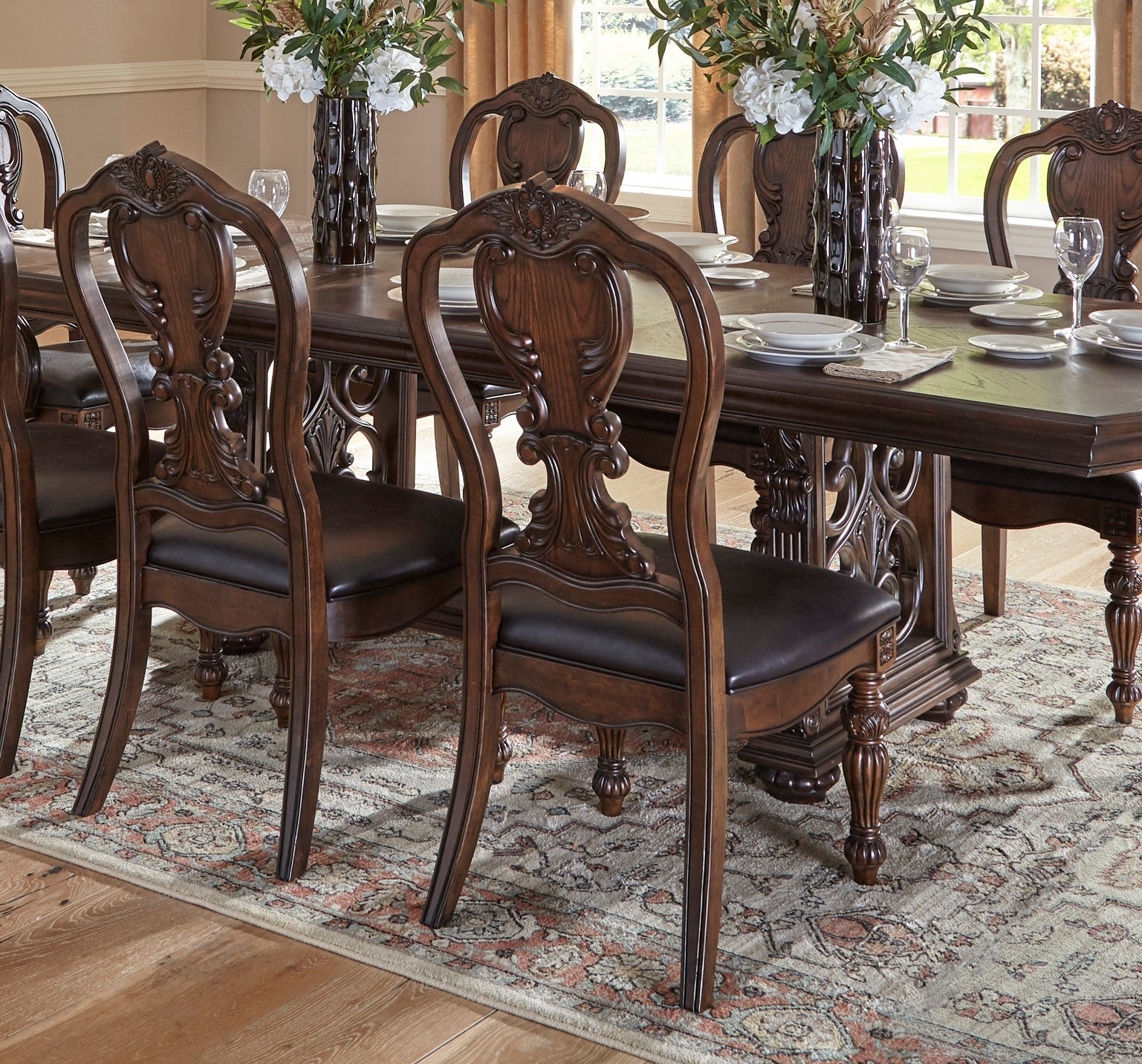 Ornate dark wood dining chairs with brown leather seats