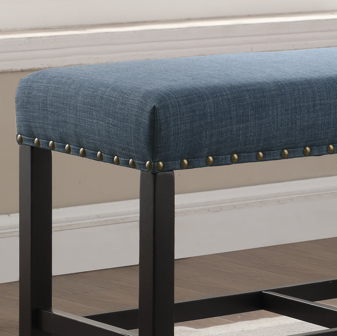 Blue upholstered bench with brass nailhead trim and dark wood legs