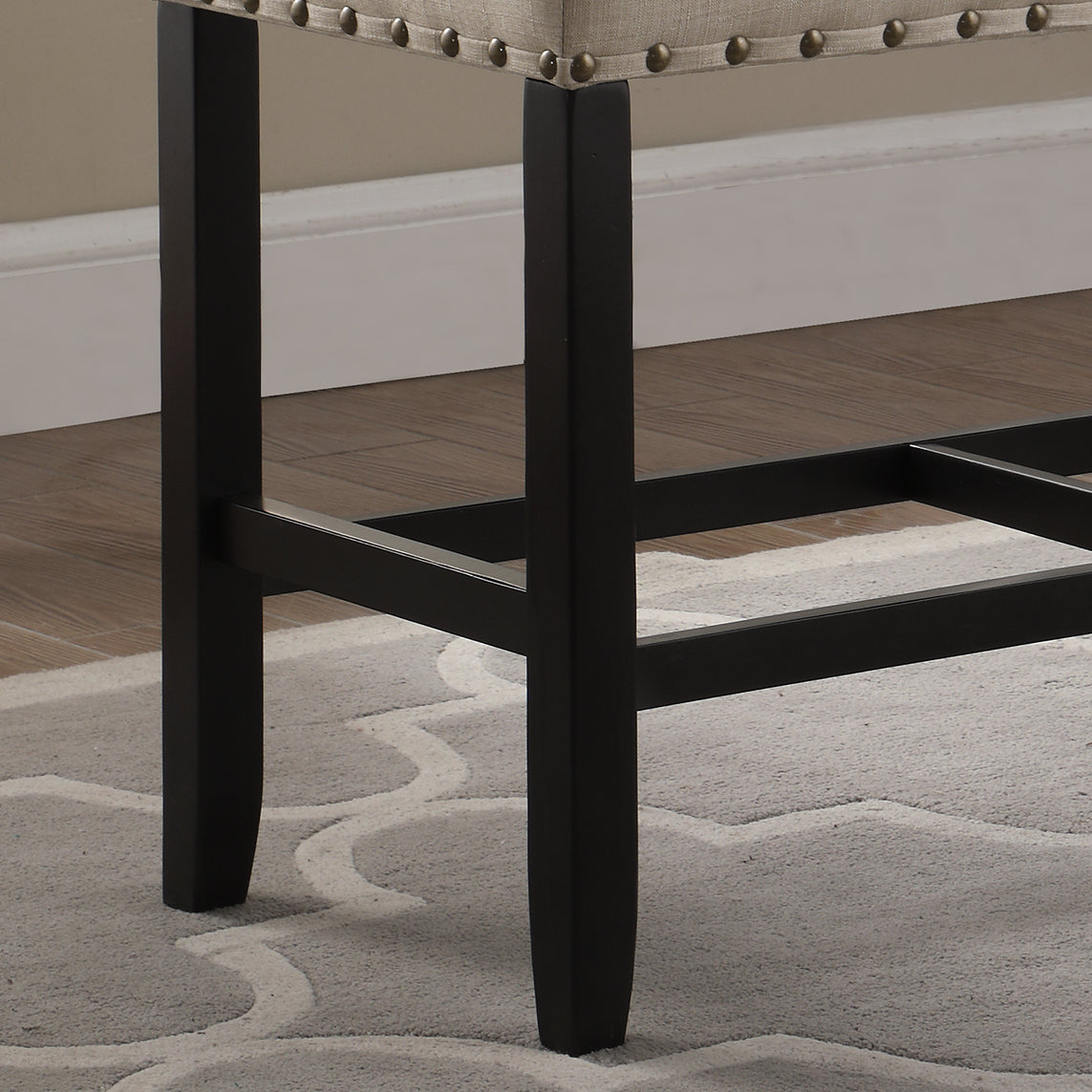 Closeup view of black wooden legs on a tufted linen bar stool