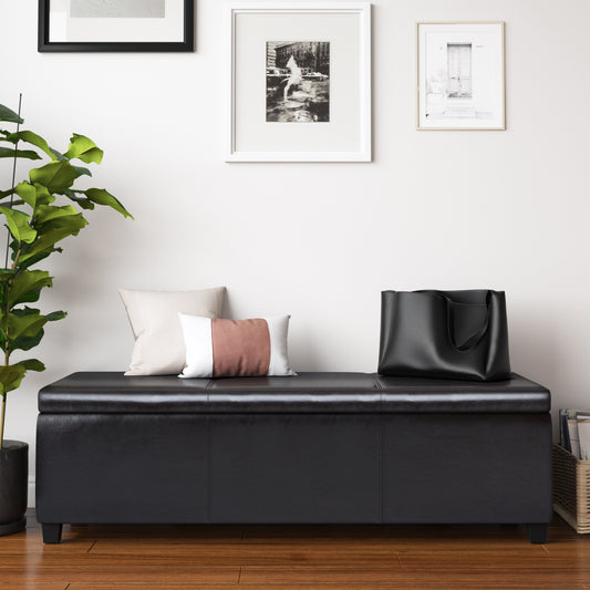 Black faux leather storage ottoman with plush pillows and tote bag