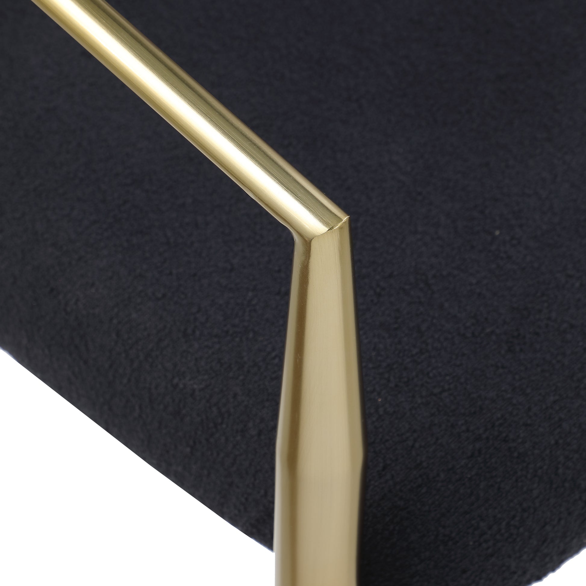 Closeup of a black textured fabric surface with a polished brass armrest