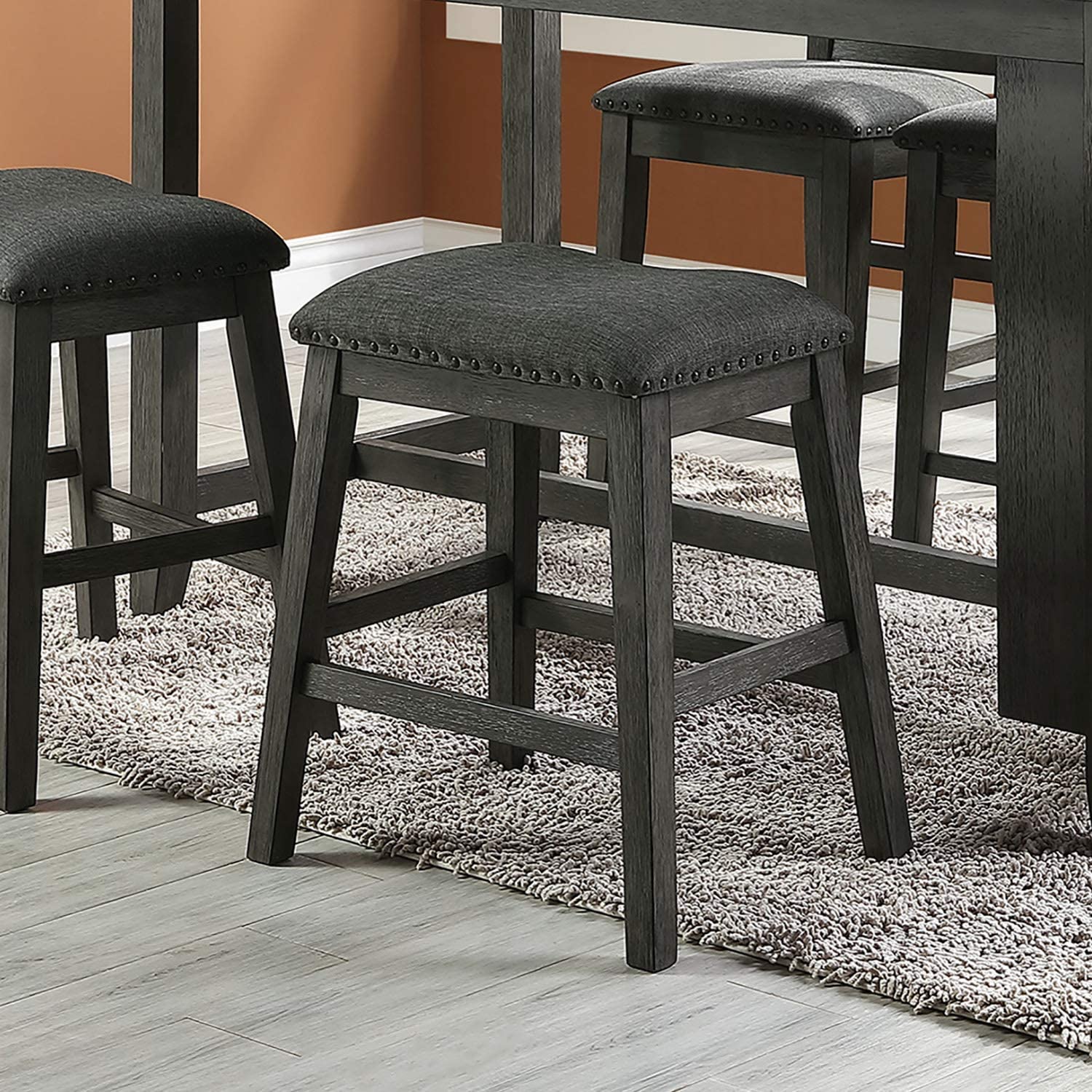Dark gray upholstered counter stool with nailhead trim and distressed wood frame