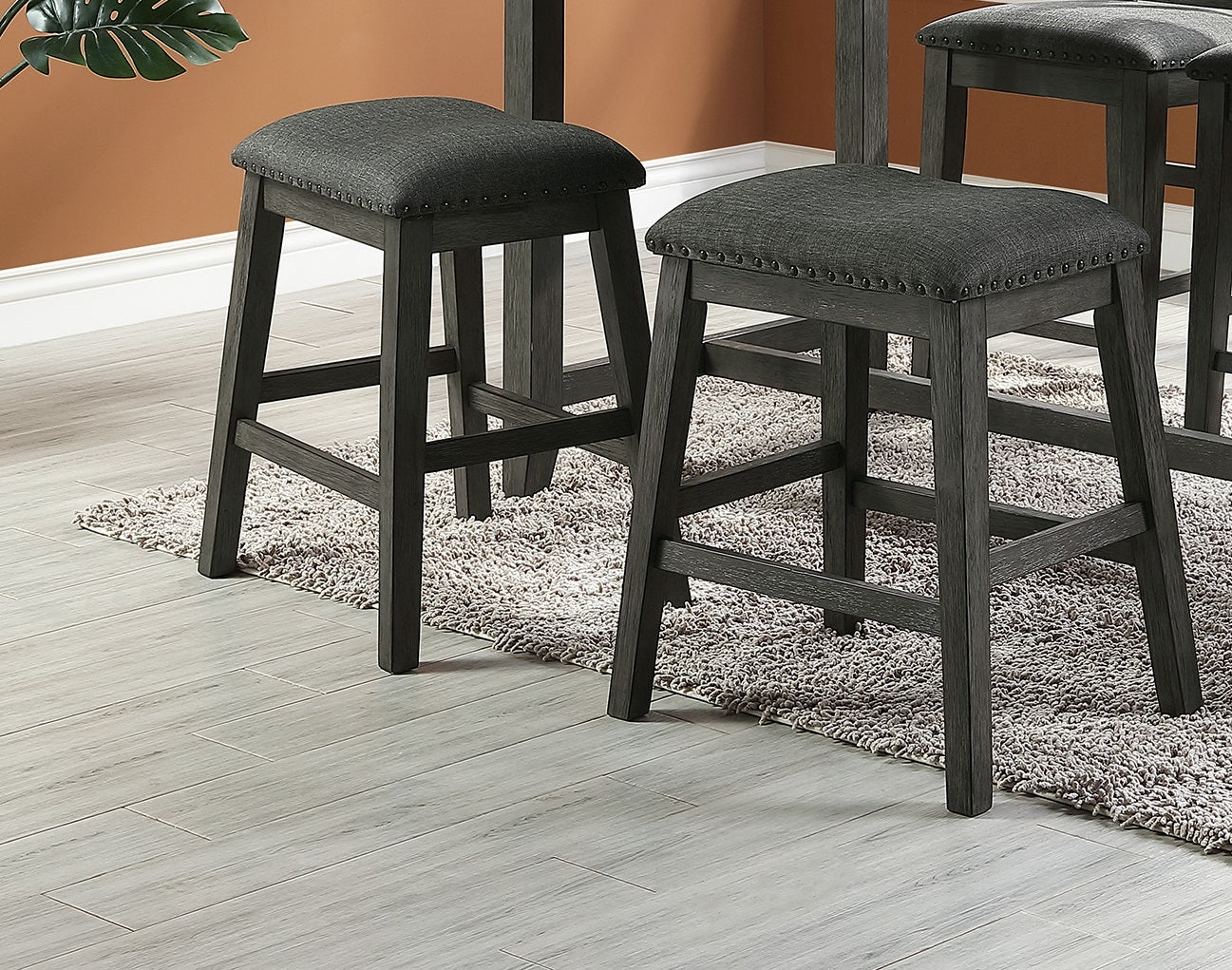 Gray upholstered counter stool with dark wood legs and nailhead trim