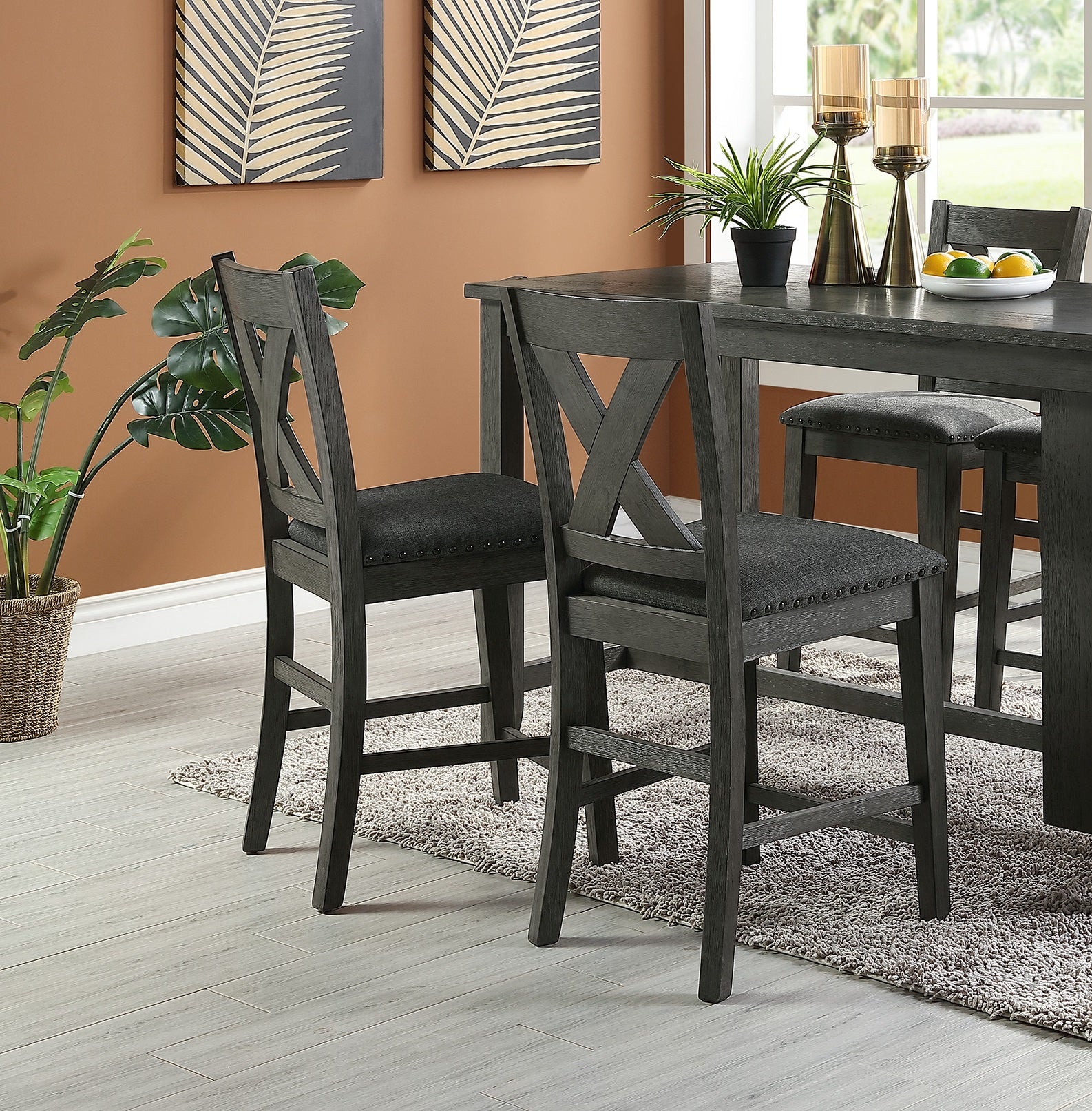 Gray wooden bar stools with dark upholstered seats and crisscross backs at a dining table