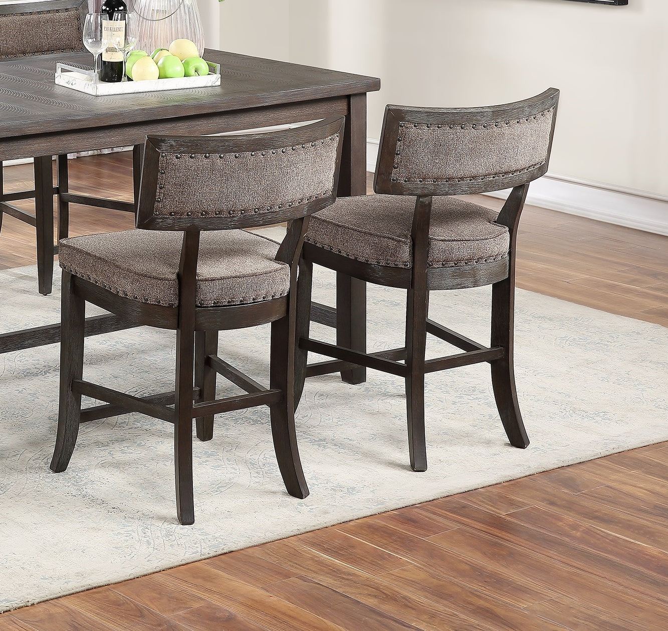 Dark brown wooden counter stools with textured fabric seats and nailhead trim