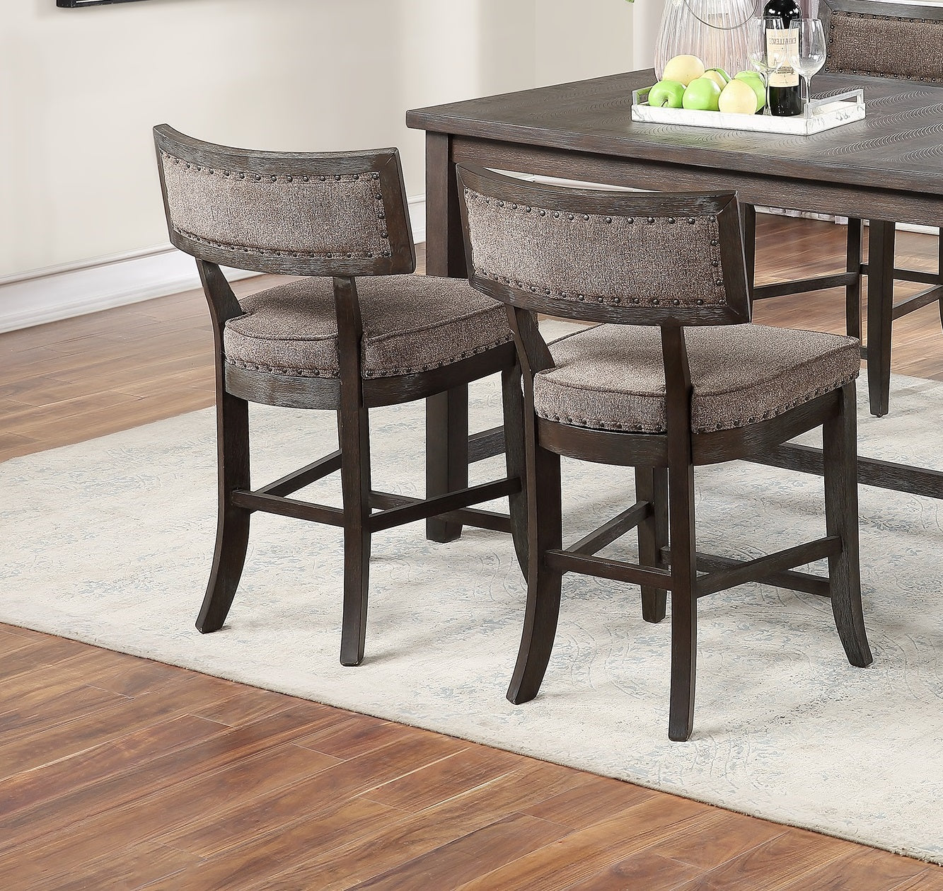 Two upholstered brown bar stools with nailhead trim flanking a dark wood dining table