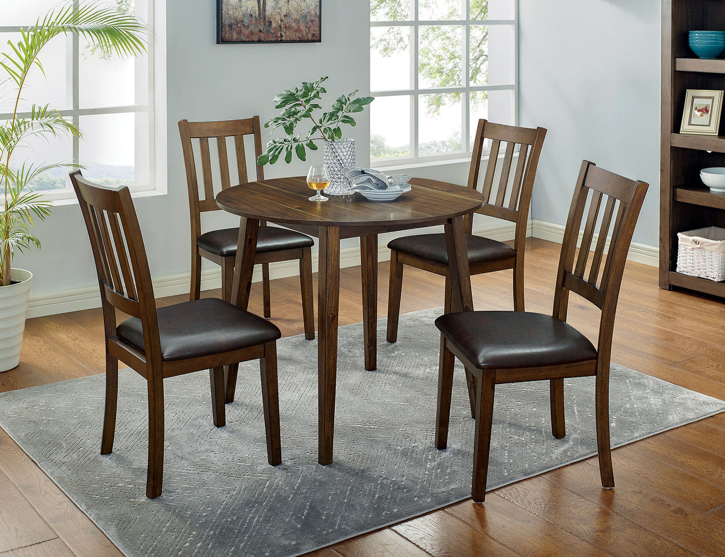 Round walnut dining table with four dark brown upholstered chairs