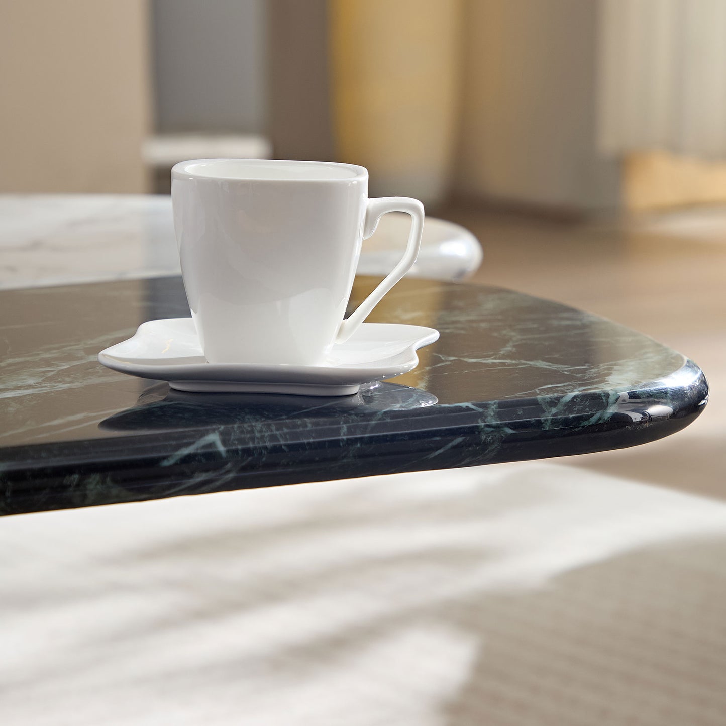 Minimalist white ceramic coffee cup and saucer on a dark green marble table