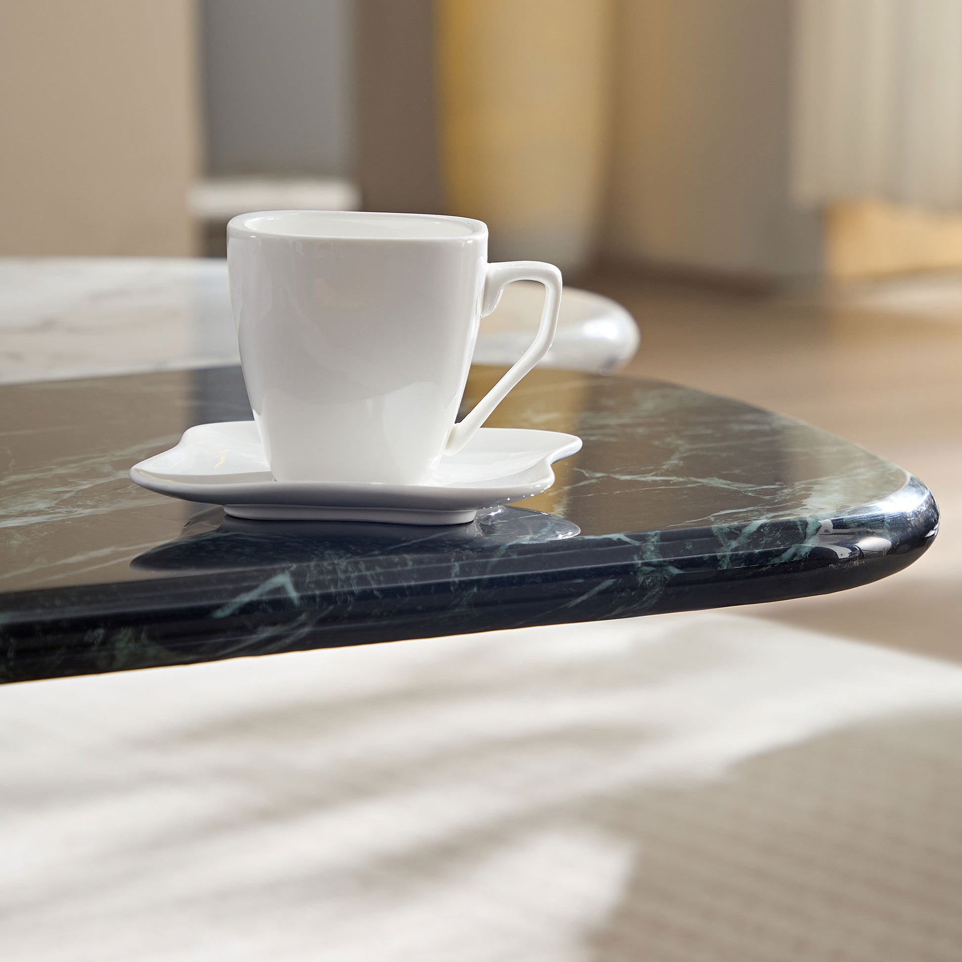 Minimalist white ceramic coffee cup and saucer on a dark green marble table