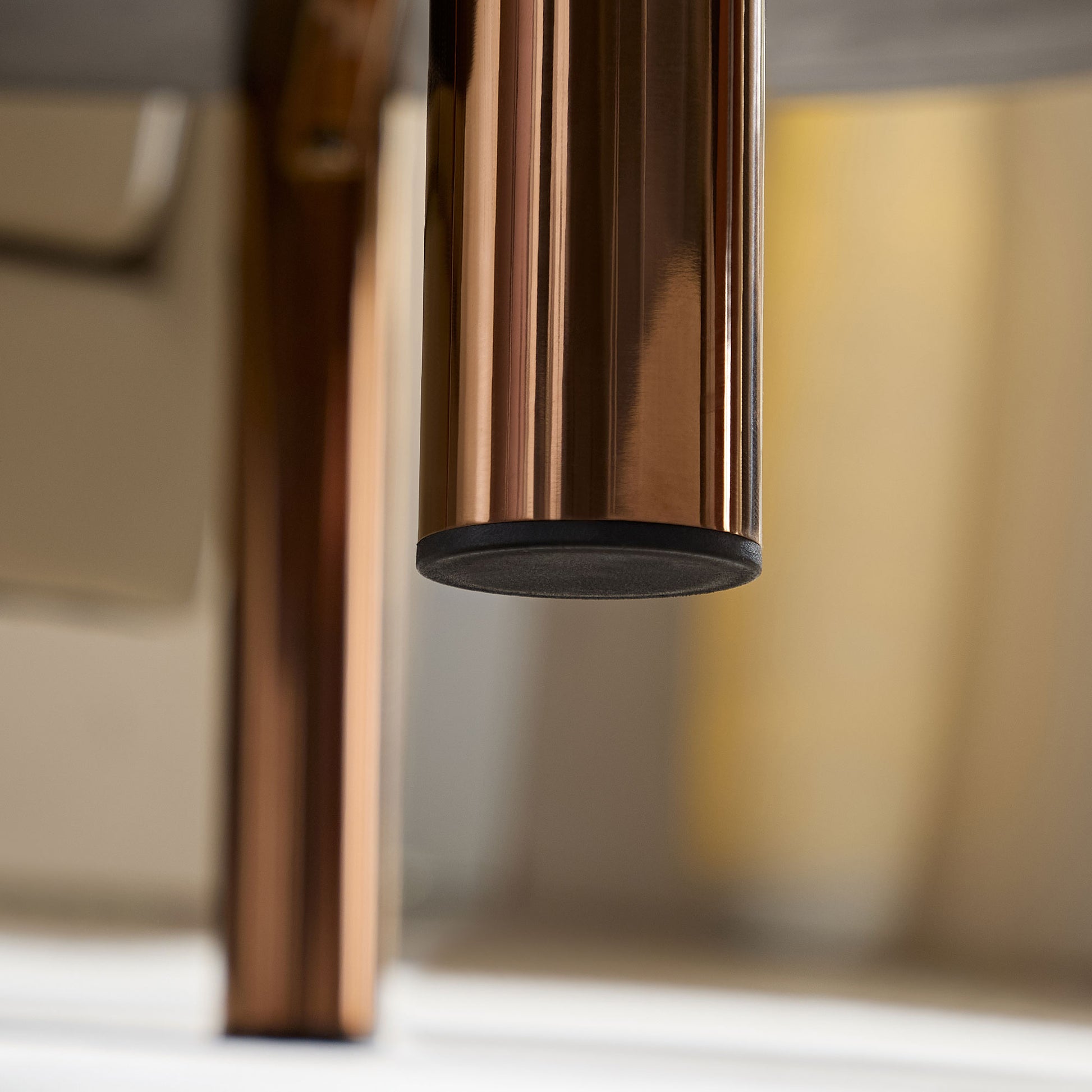 Closeup of polished copper furniture leg with black rubber foot