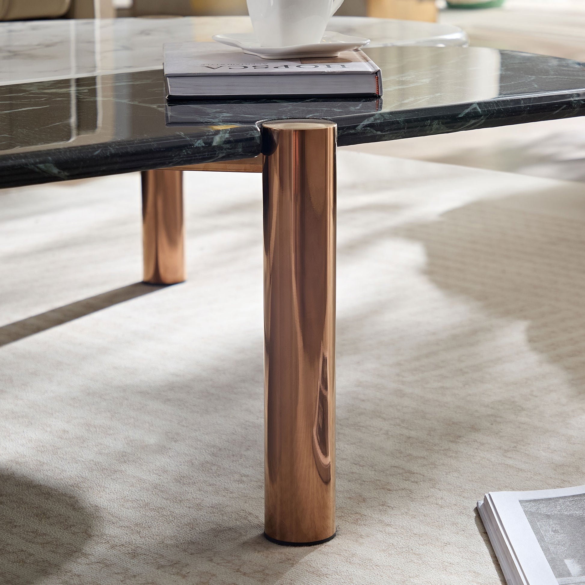 Dark green marble coffee table with polished rose gold legs on plush rug