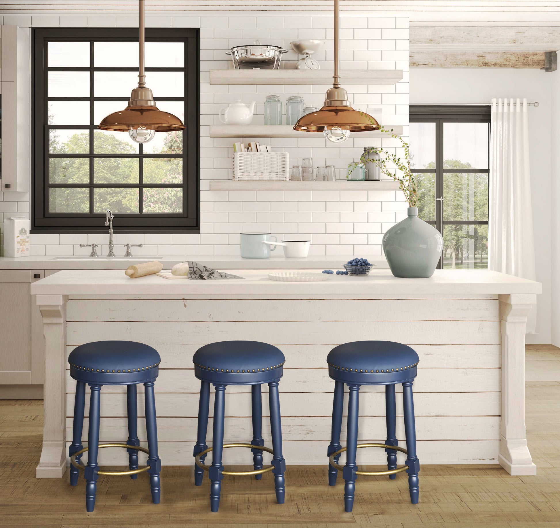 Three navy blue upholstered bar stools with brass footrests surround a white kitchen island