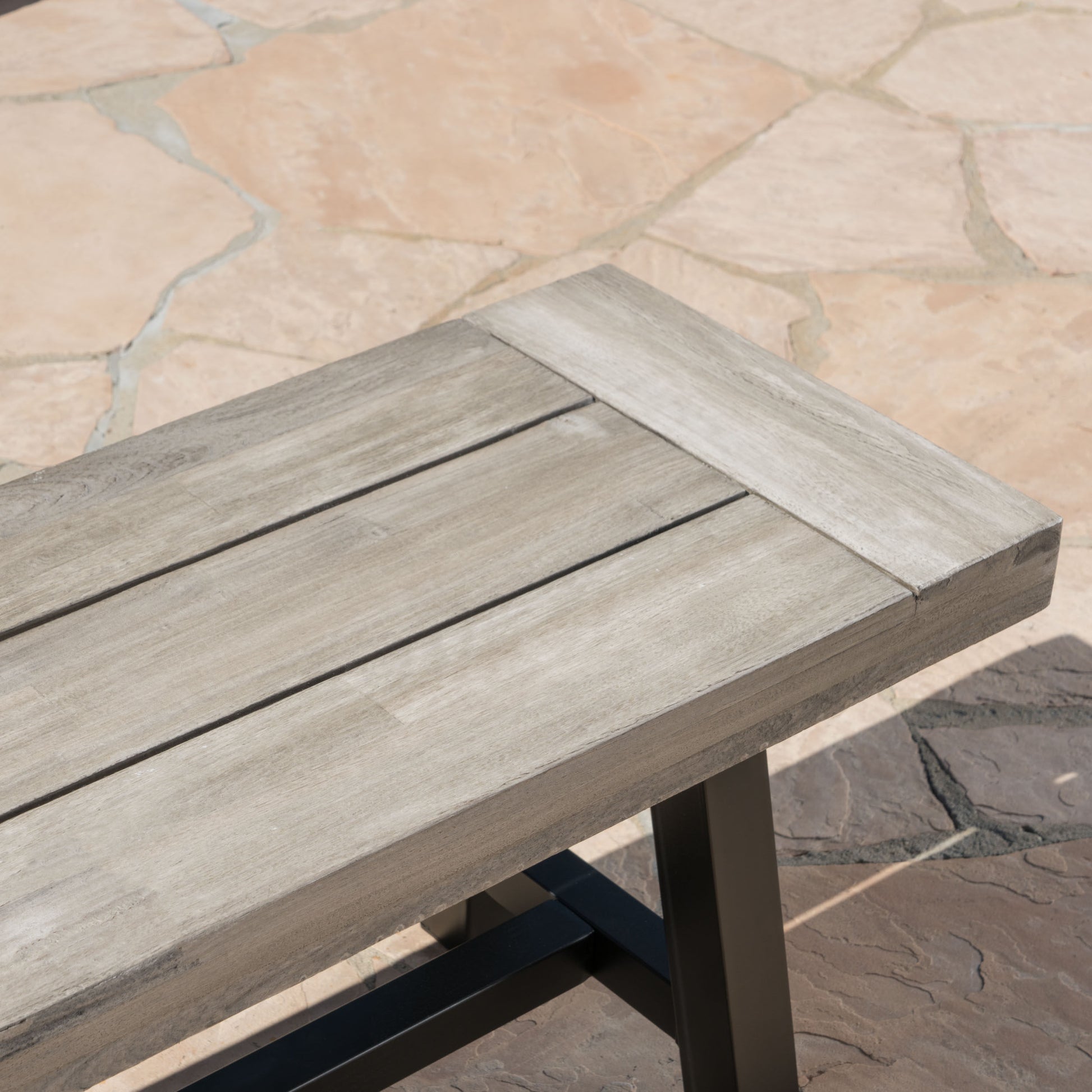 weathered gray wooden bench with black metal legs