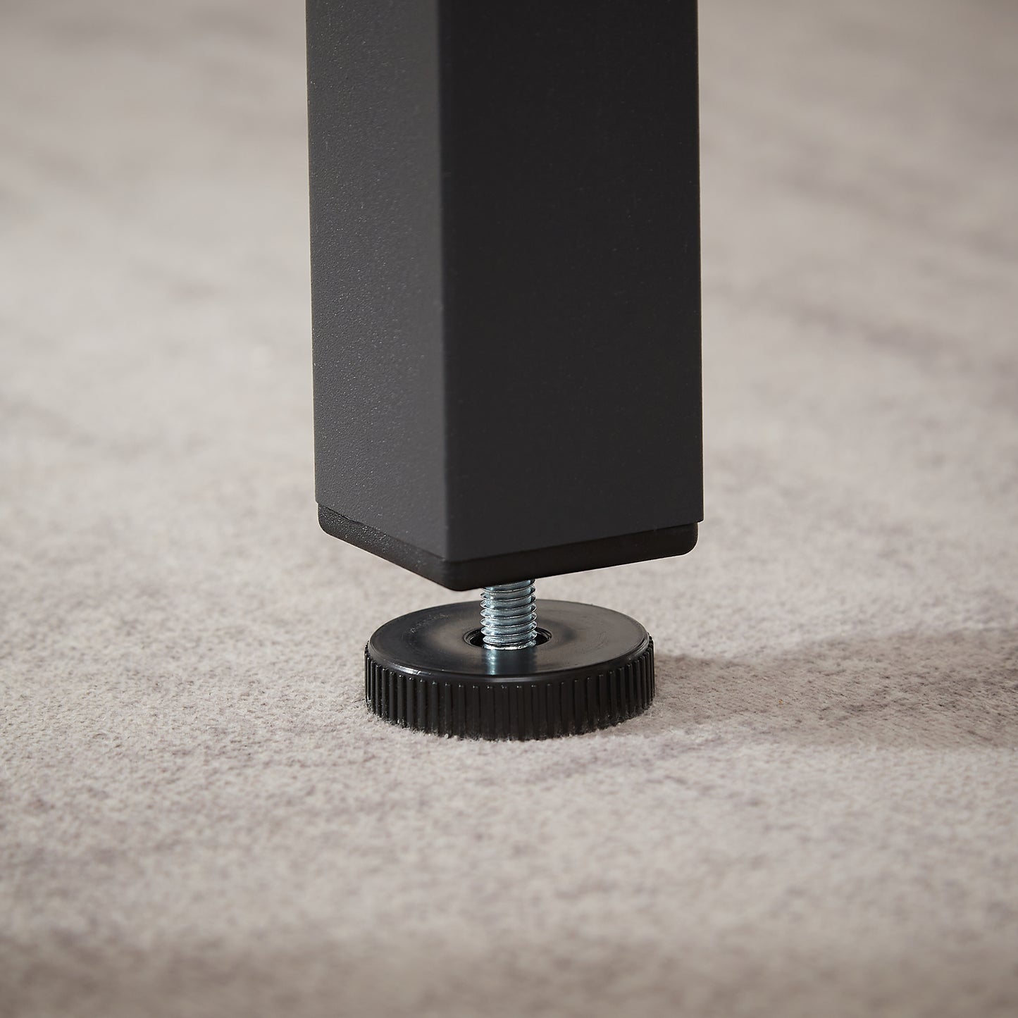 Black adjustable furniture foot with threaded screw on textured floor