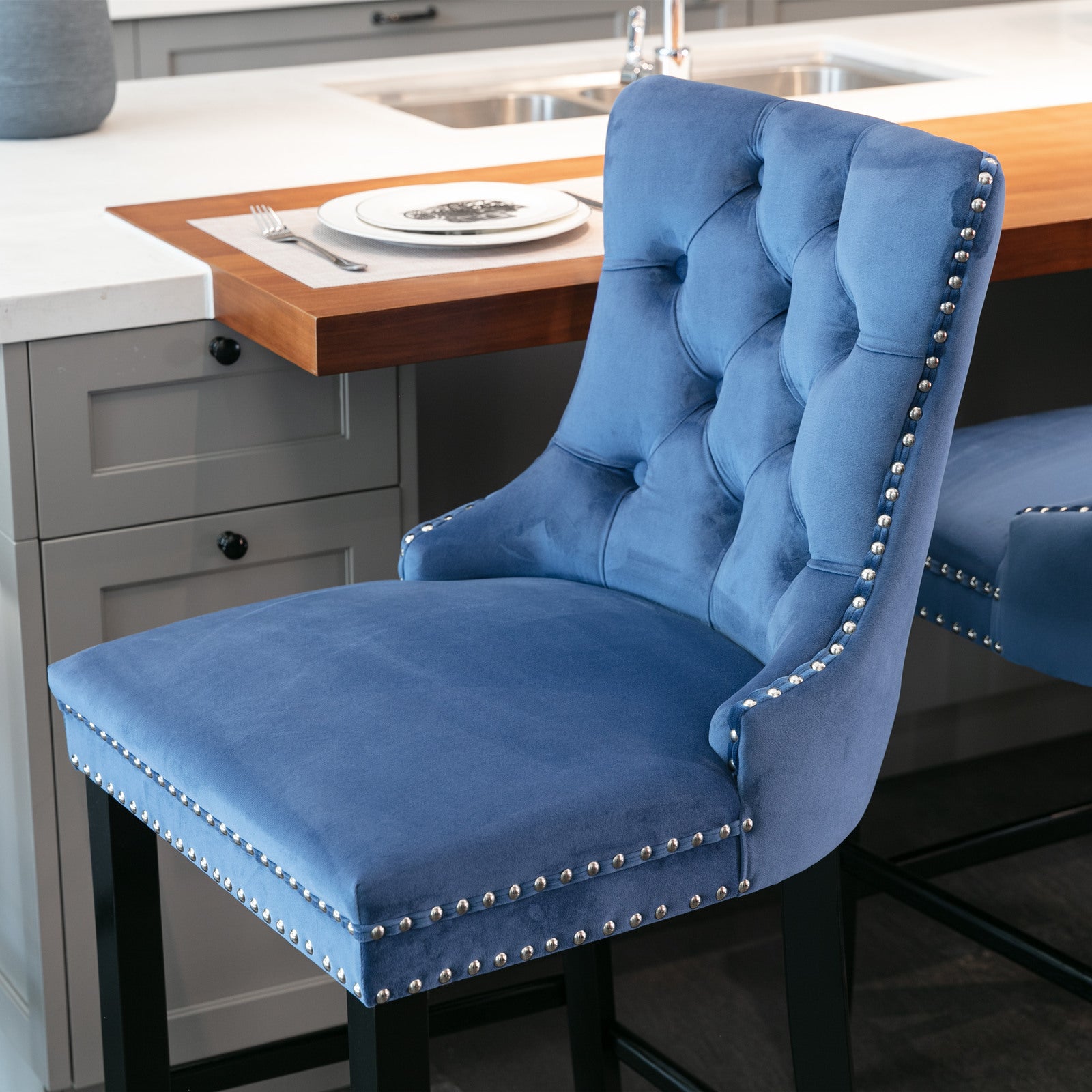 Blue velvet tufted bar stool with silver nailhead trim and black legs