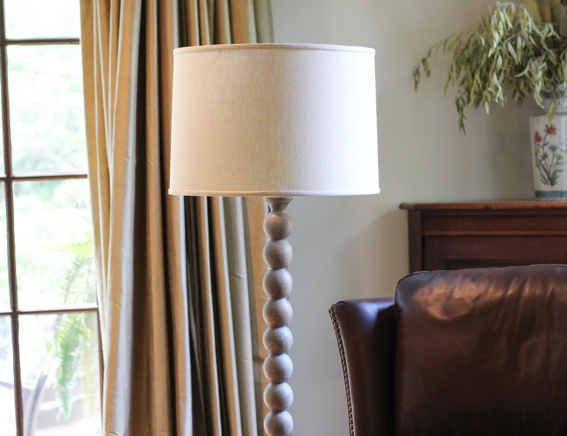Modern wooden floor lamp with white drum shade and stacked spherical base