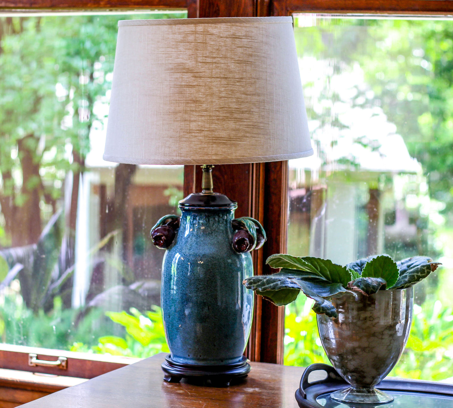 Teal ceramic table lamp with decorative handles and natural linen shade