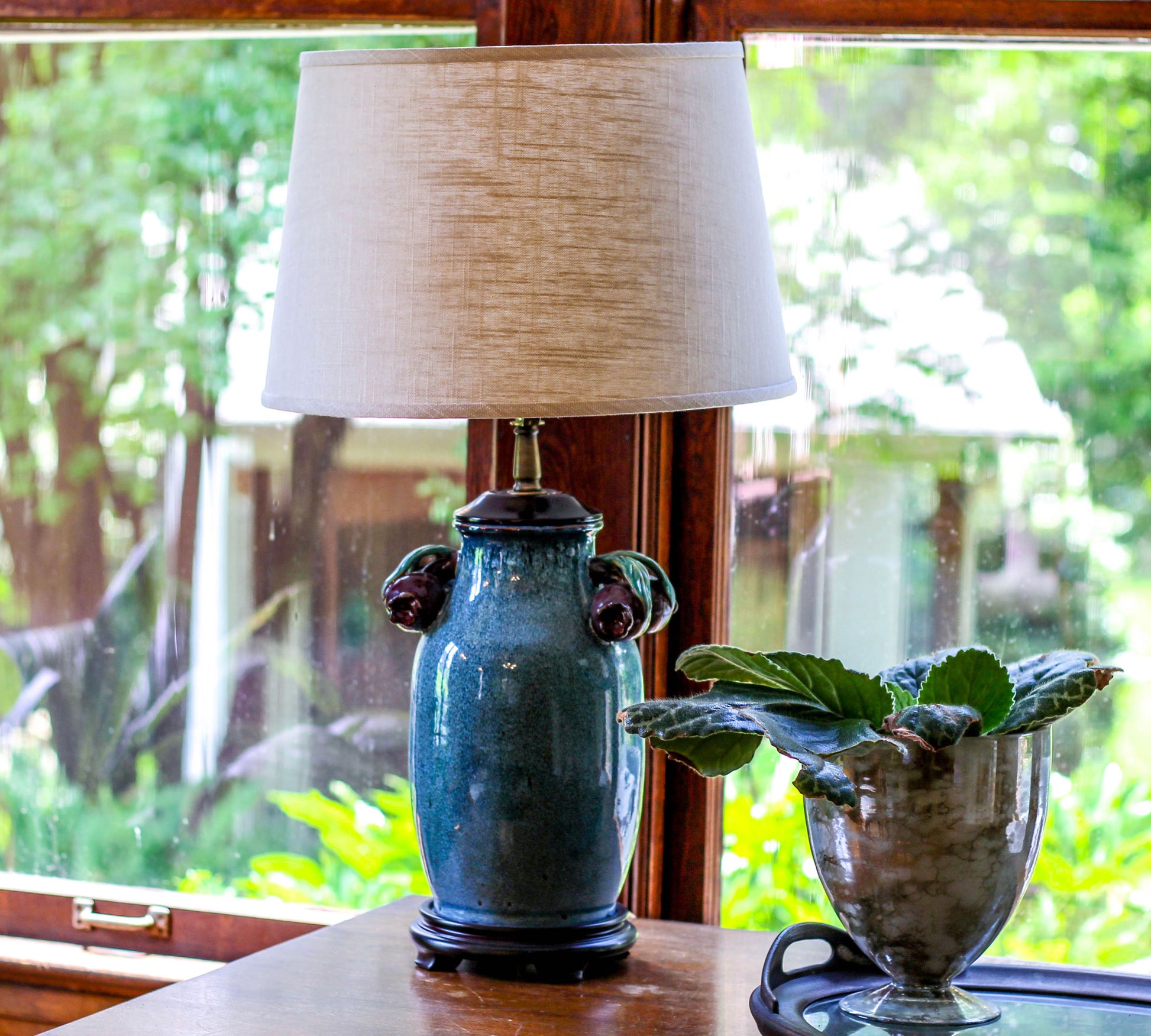 Teal ceramic table lamp with decorative handles and natural linen shade